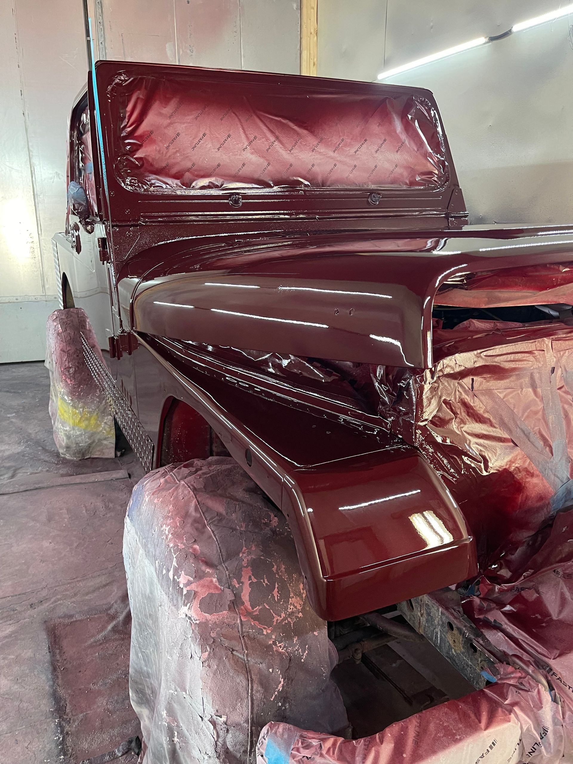A red jeep is being painted in a garage.