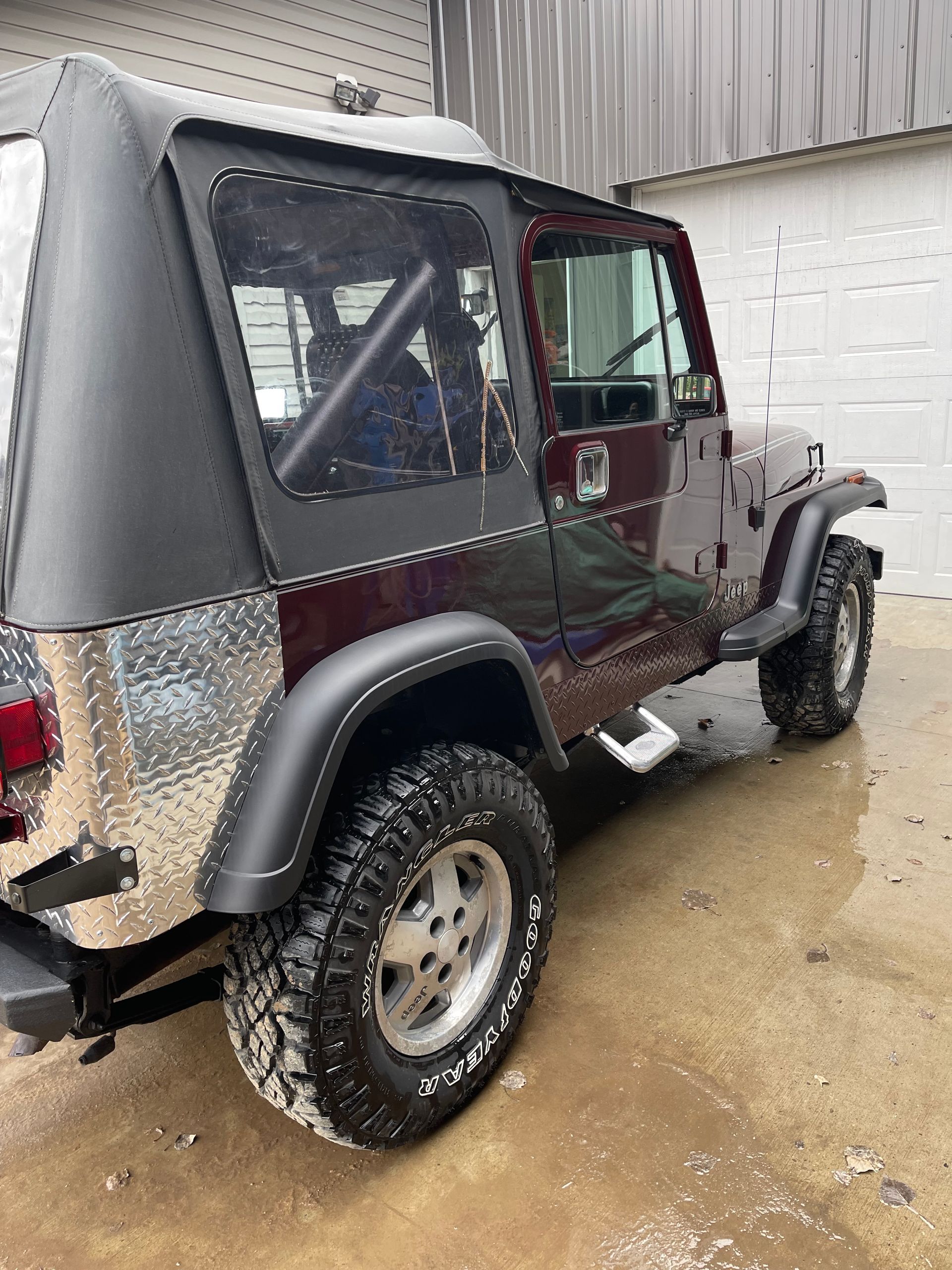 A red jeep is parked in front of a garage.