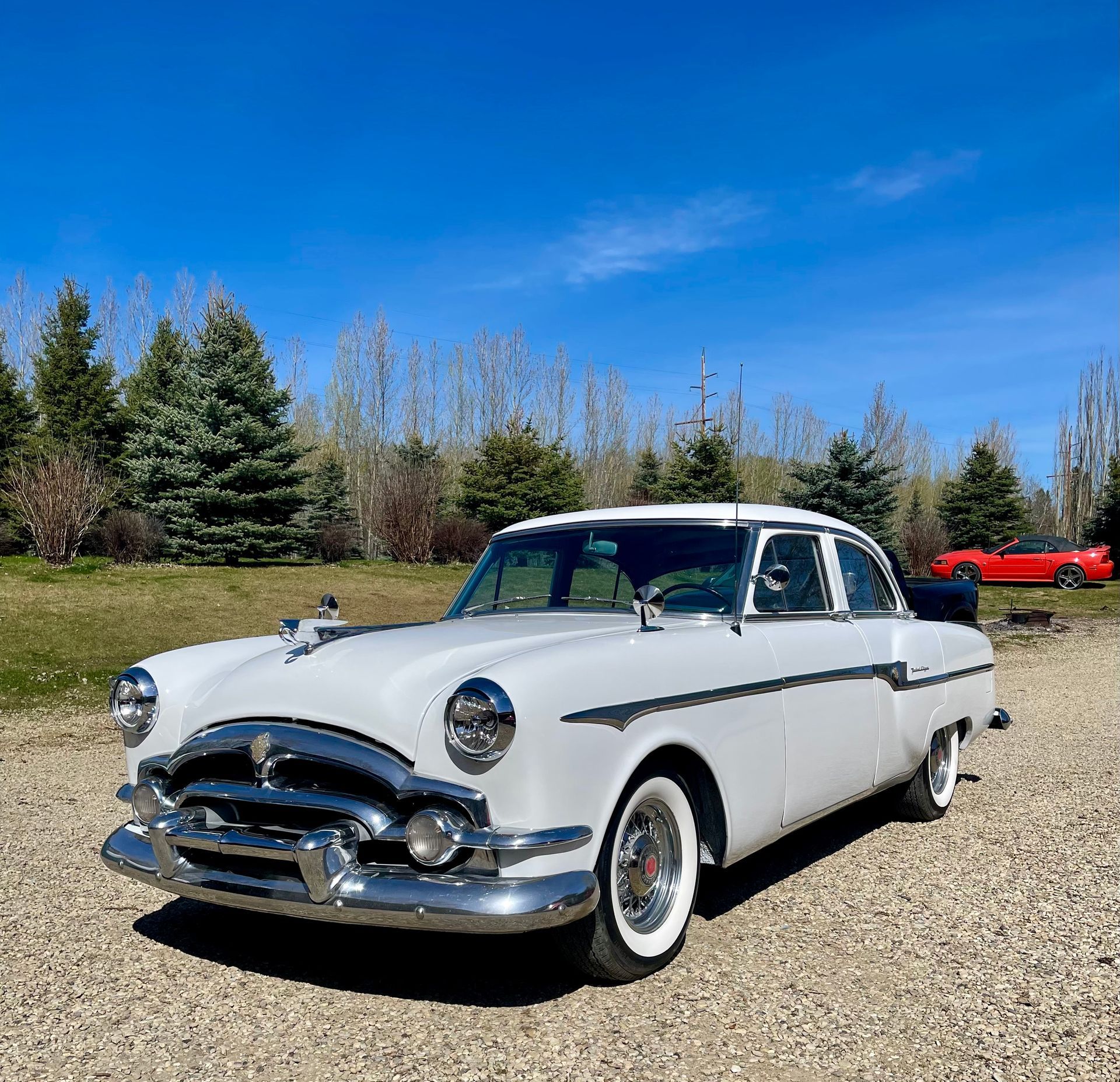 A white car is parked on a gravel road