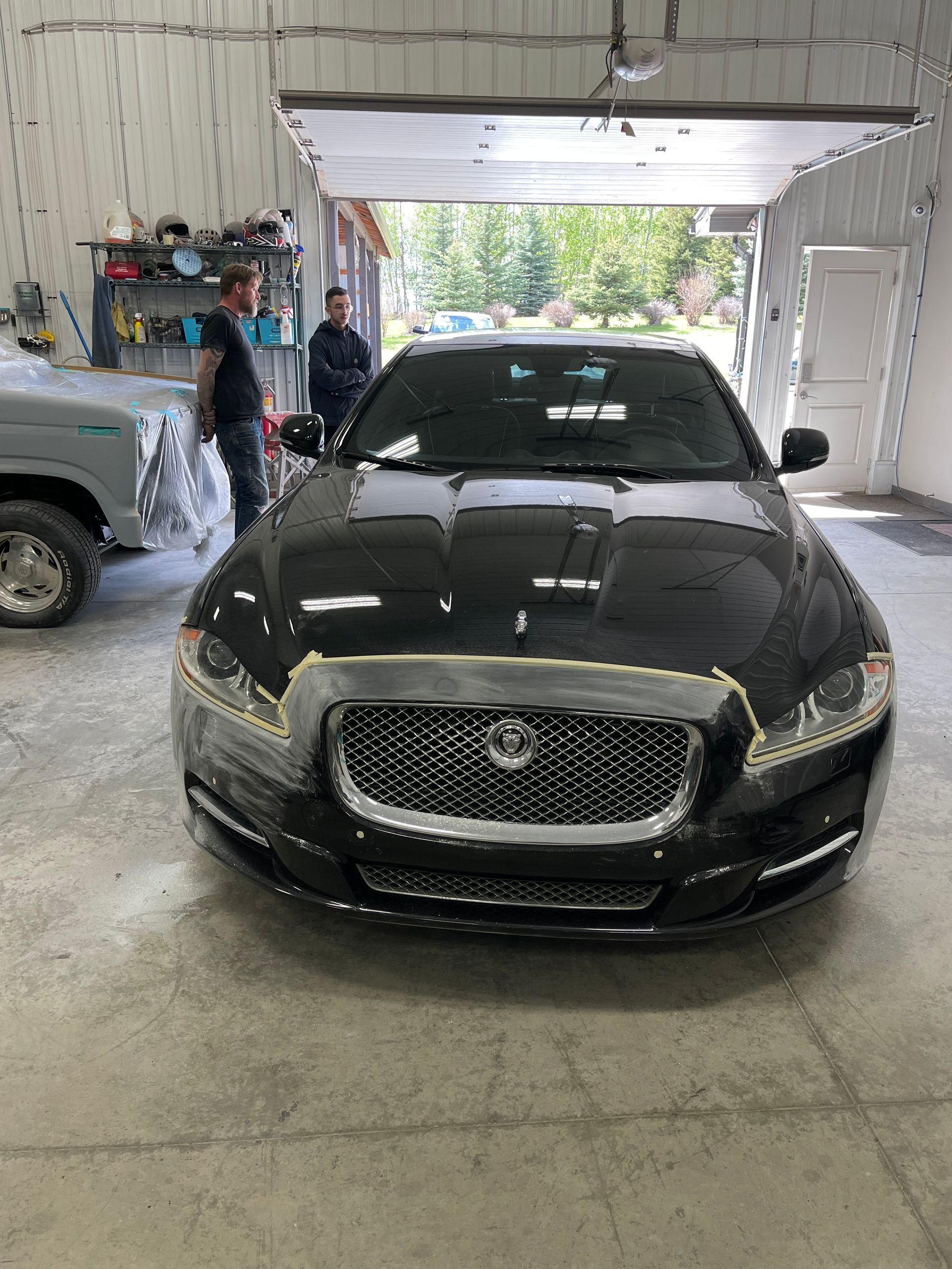 A black car is sitting in a garage with a man standing next to it.