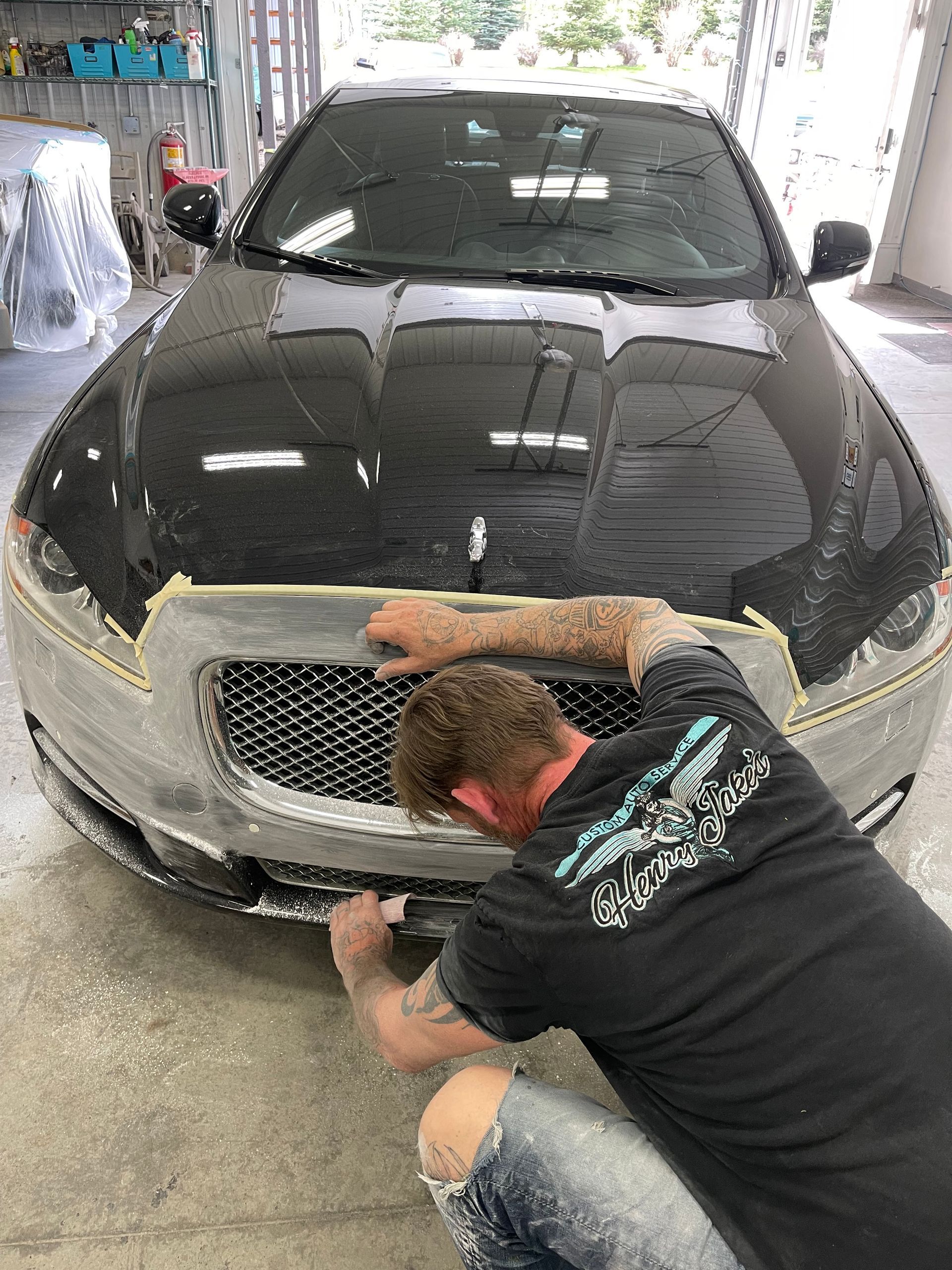 A man is working on the front of a black car.