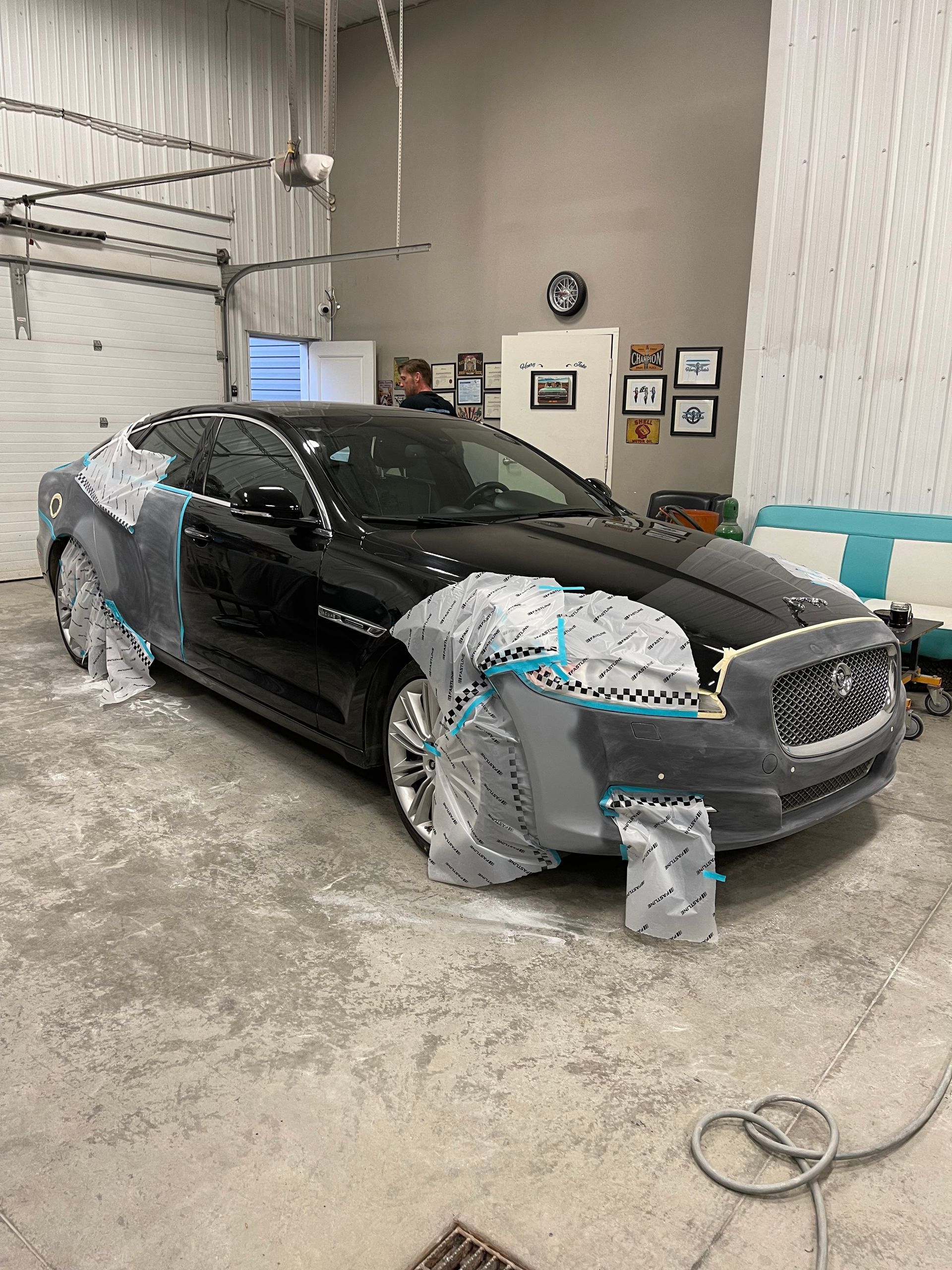 A black car is being painted in a garage.
