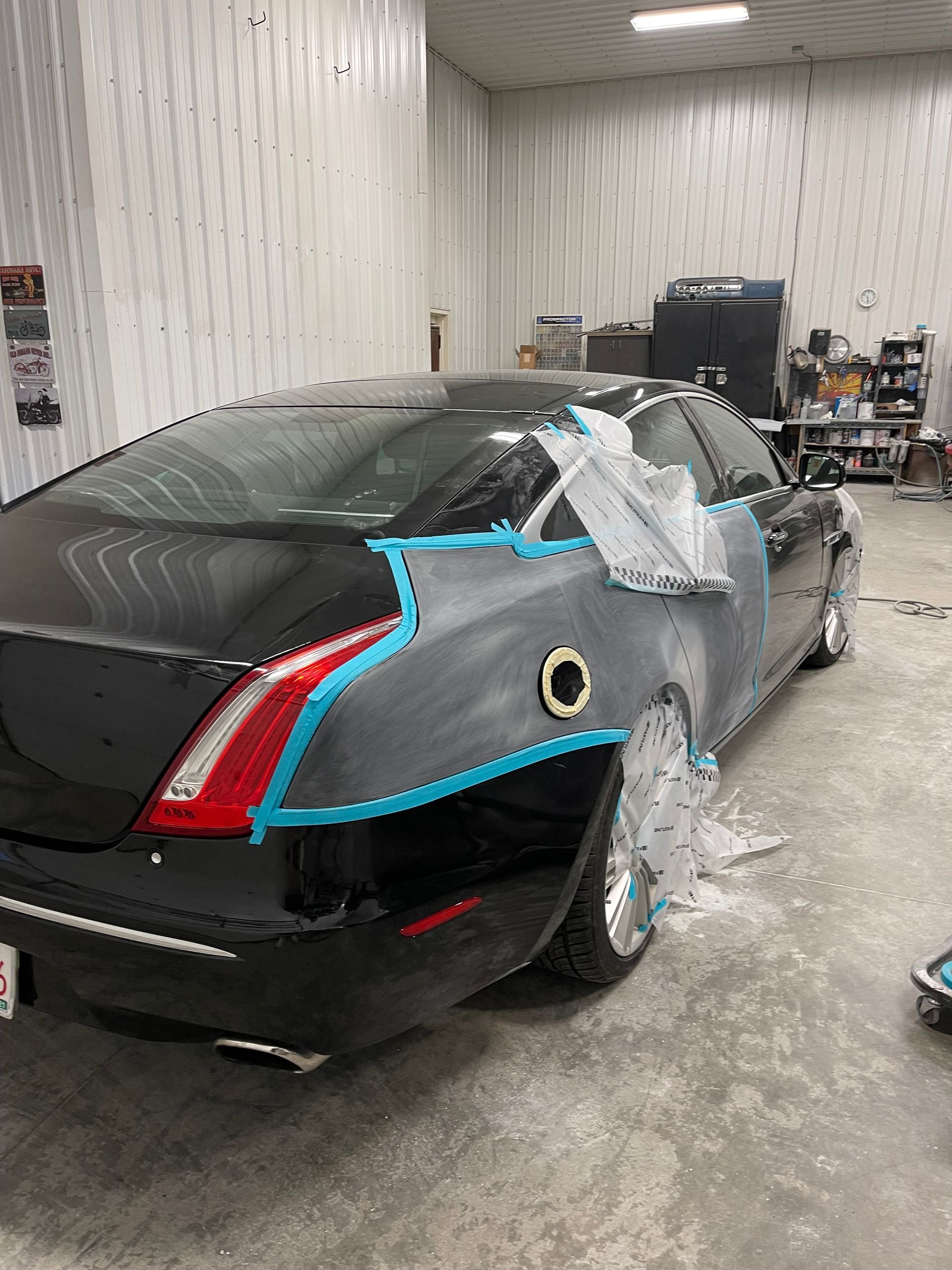 A black car is being painted in a garage.