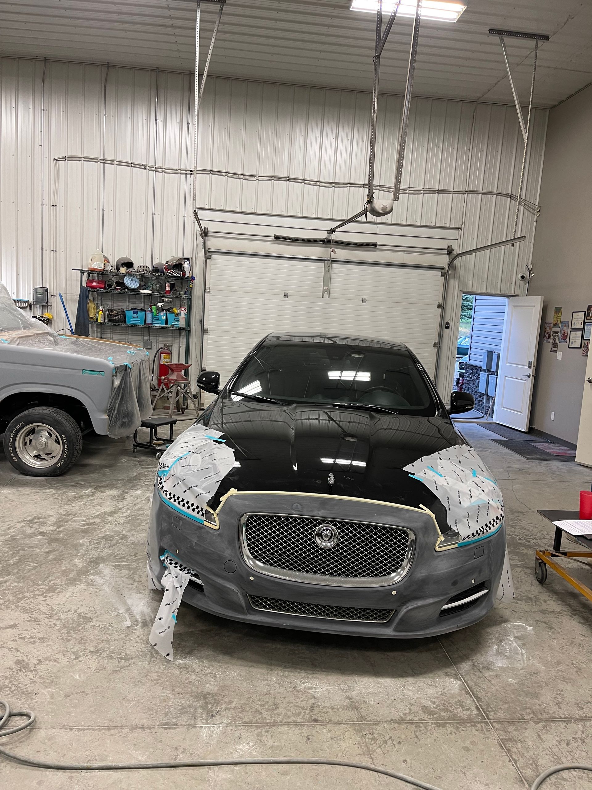 A black car is being painted in a garage.