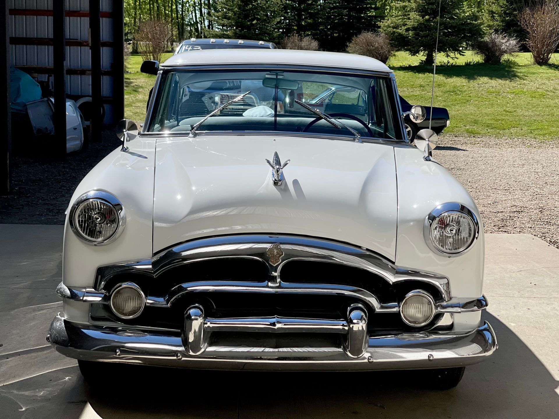 A white car with a star on the hood is parked in a driveway