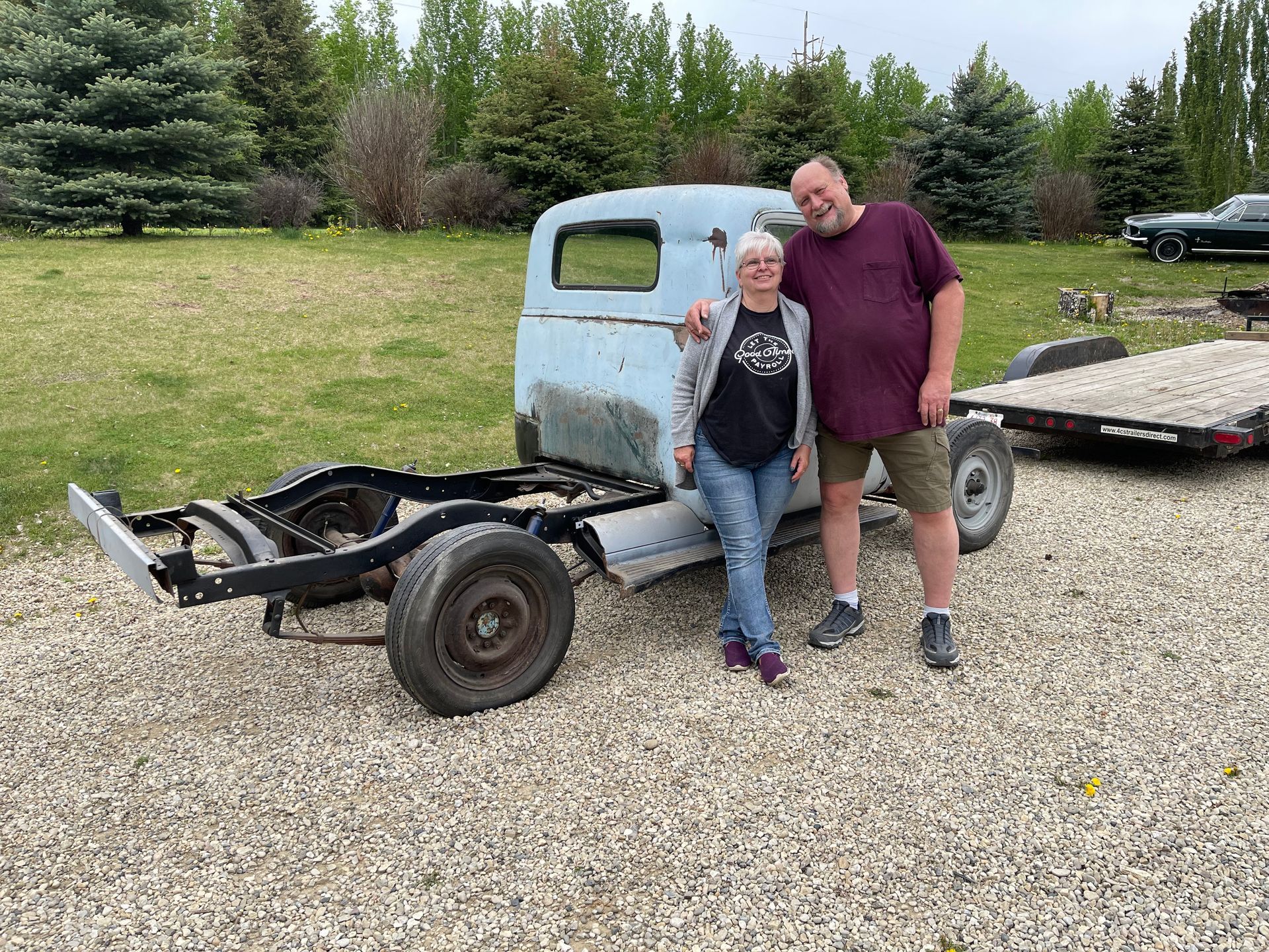 A man and a woman are standing in front of an old truck.