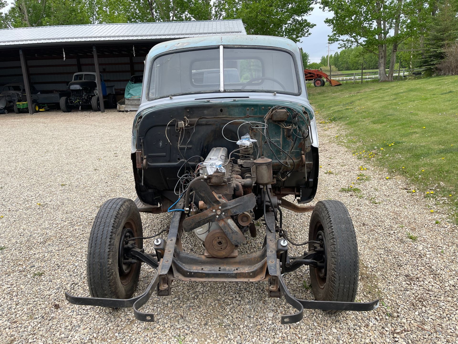 A car with the engine removed is sitting on a gravel road.