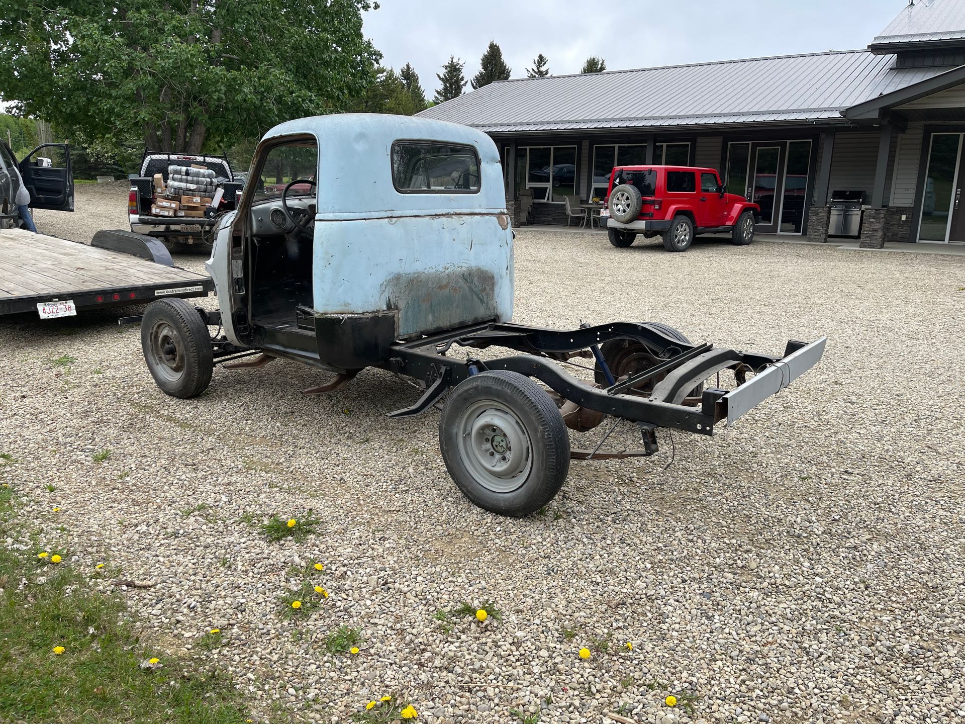 A blue truck is parked in a gravel lot in front of a building.