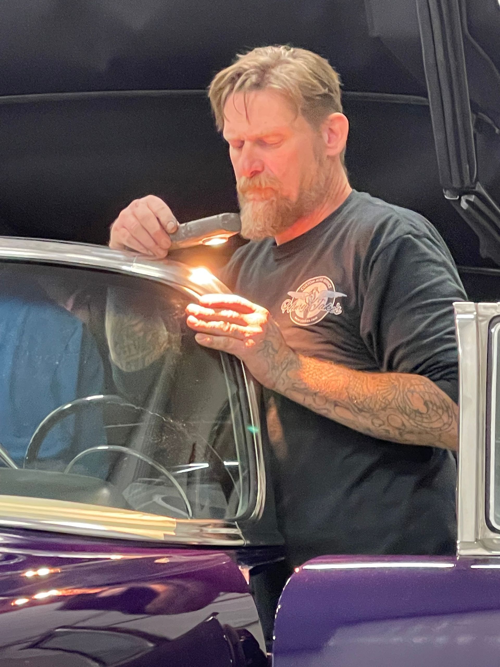A man in a black shirt is working on a purple car