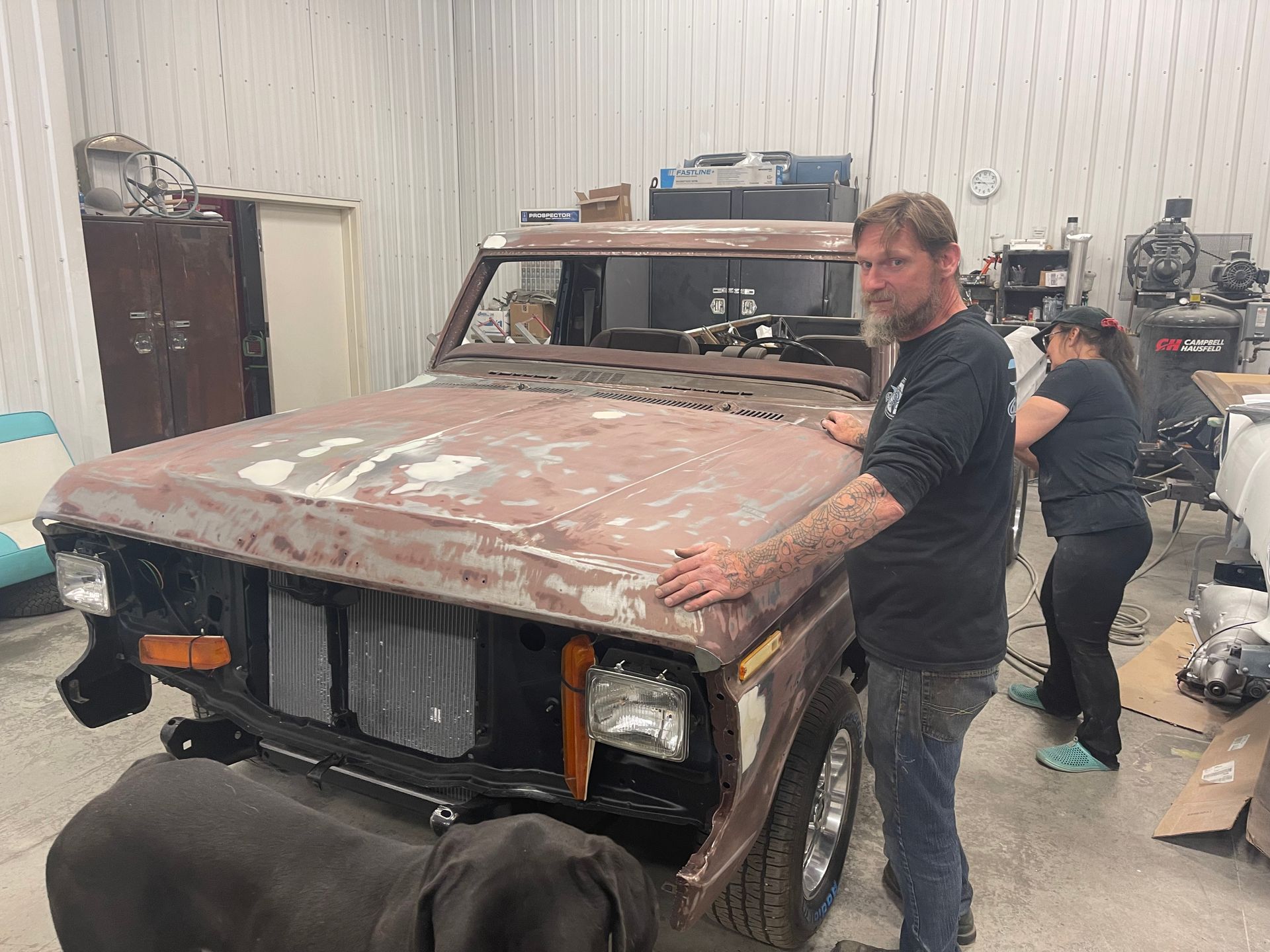 A man is standing next to a jeep in a garage.