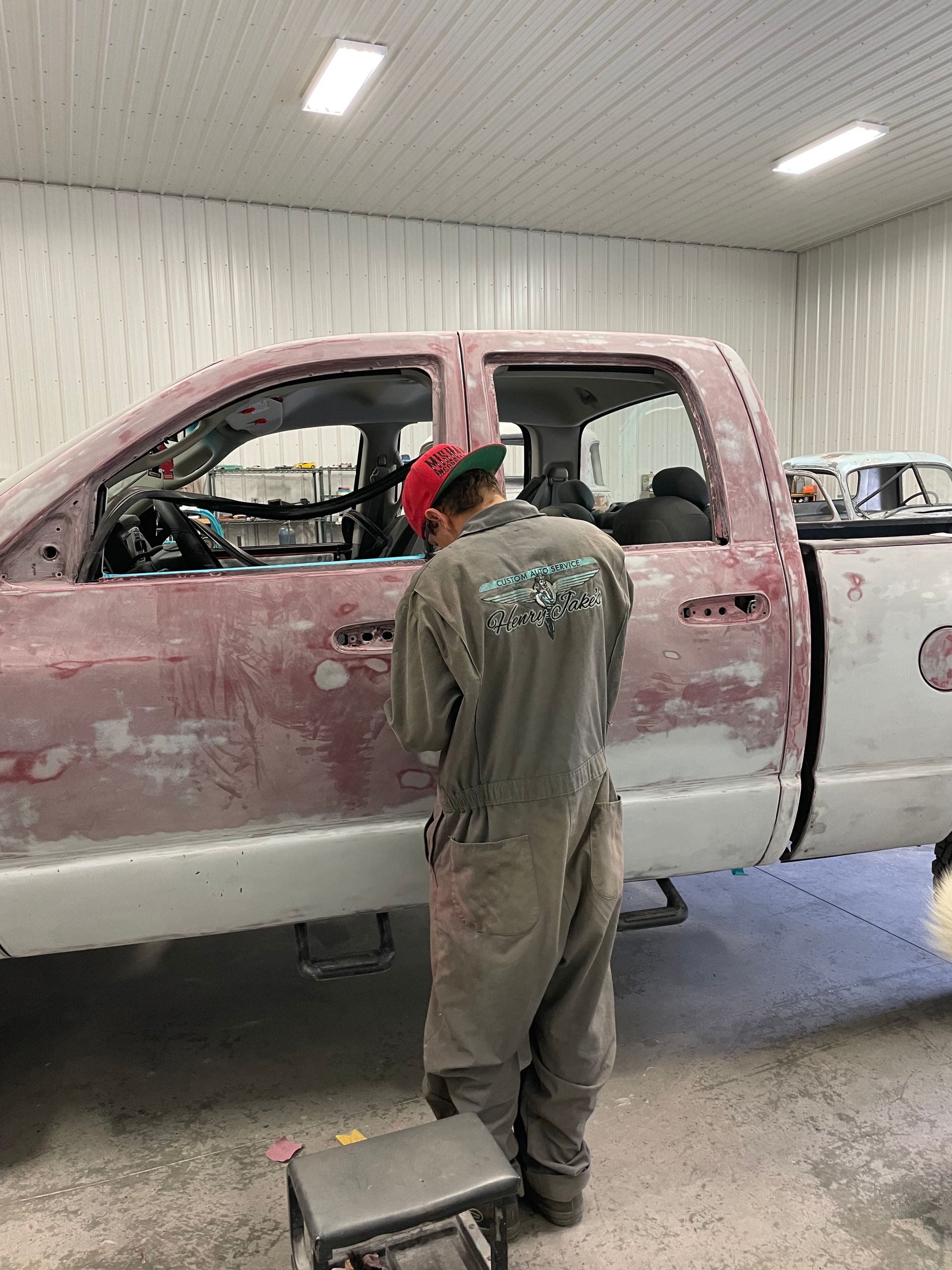 A man is working on a pink truck in a garage.