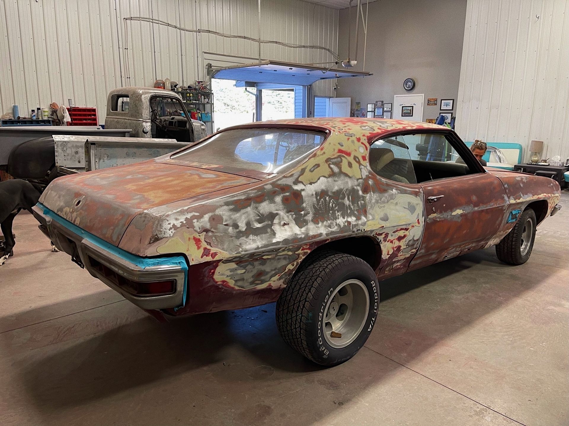A rusty old car is sitting in a garage.
