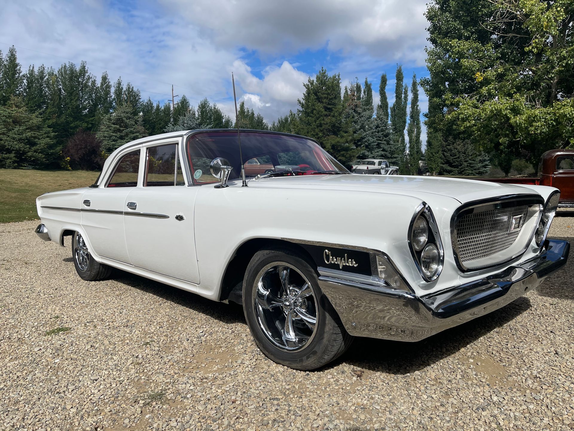 A white car is parked on a gravel road.