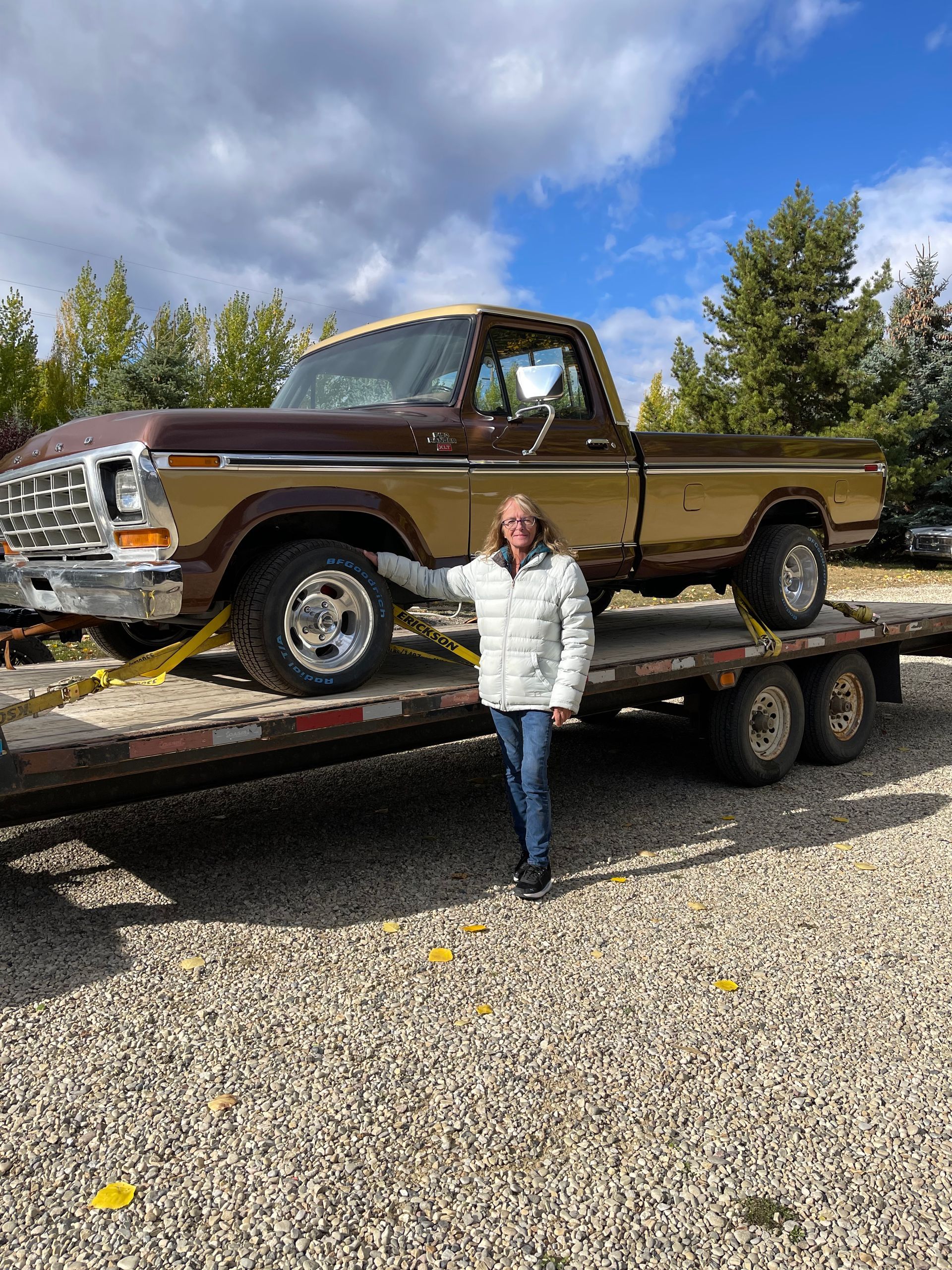 A woman is standing next to a truck on a trailer.