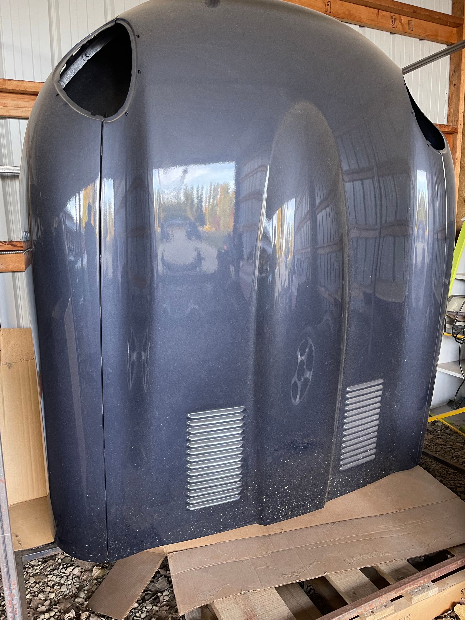 A large black hood is sitting on top of a wooden pallet.