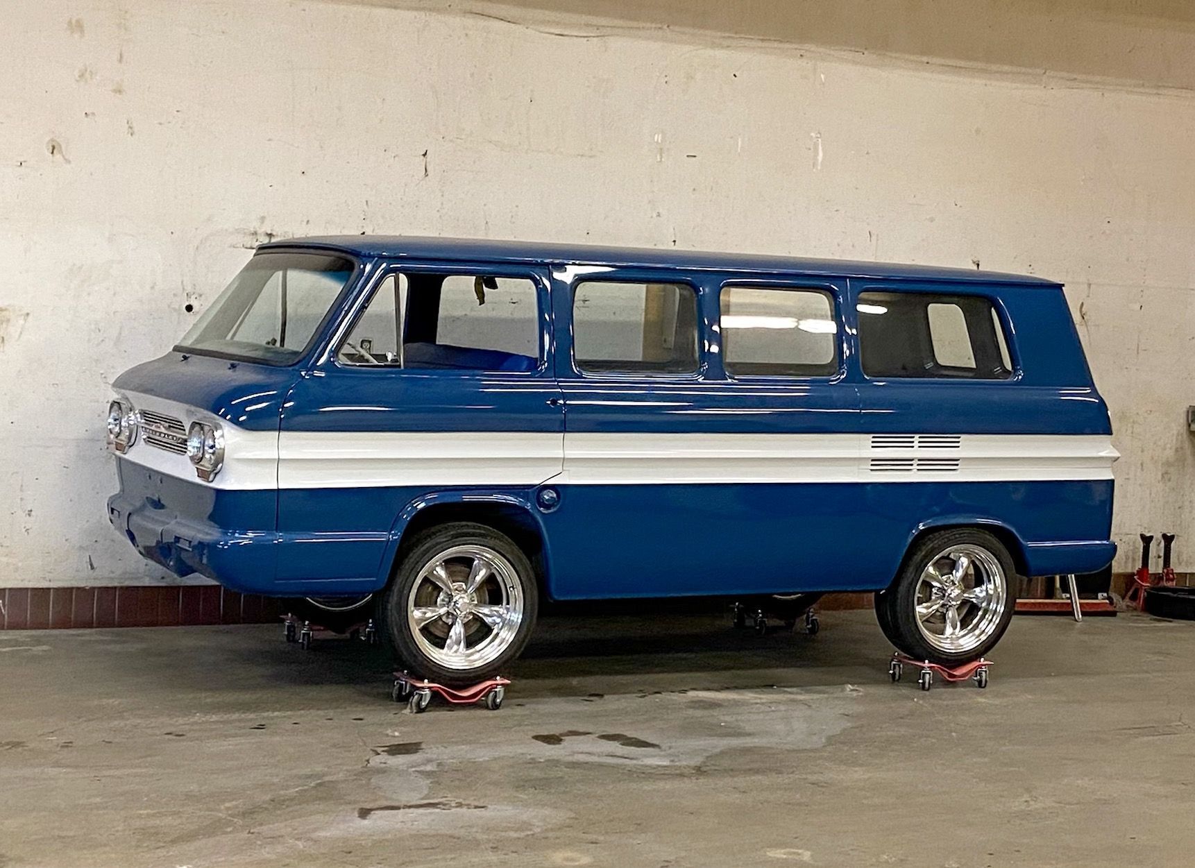 A blue van is parked on wheels in a garage