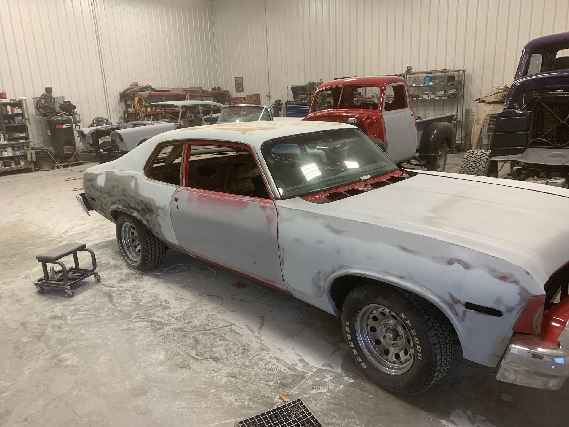 A white car is being painted in a garage.