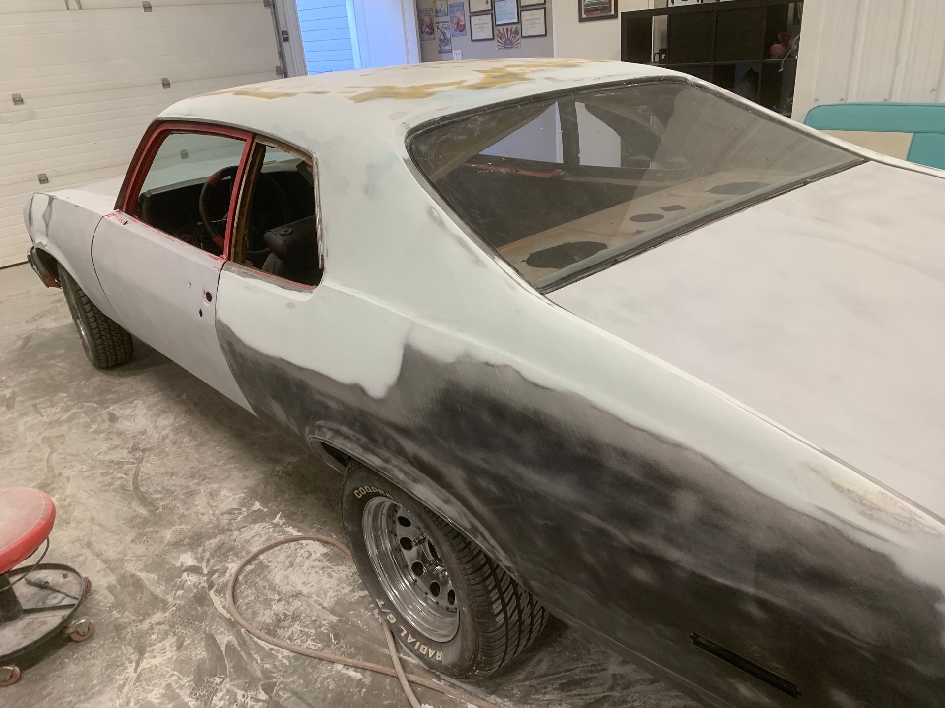 A white car is being painted in a garage.