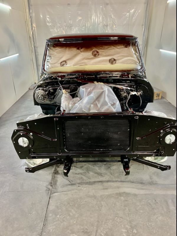 A car is being painted in a paint booth with the hood open.