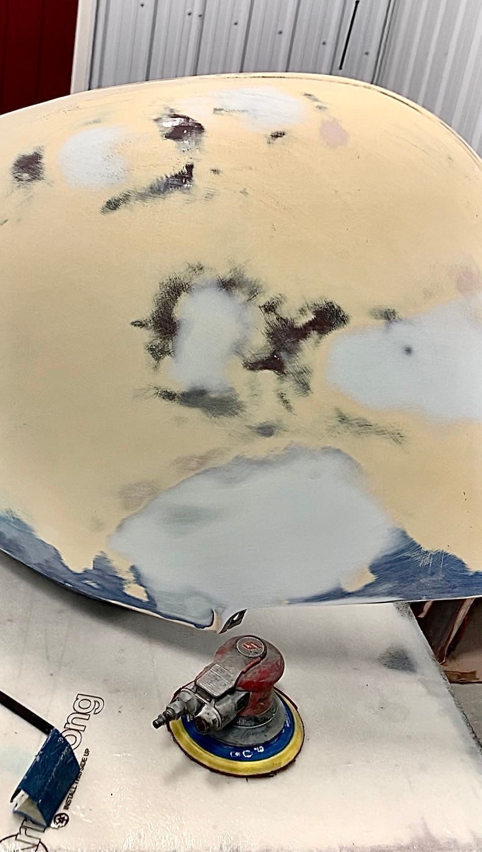 A piece of metal is sitting on a table next to a sander.