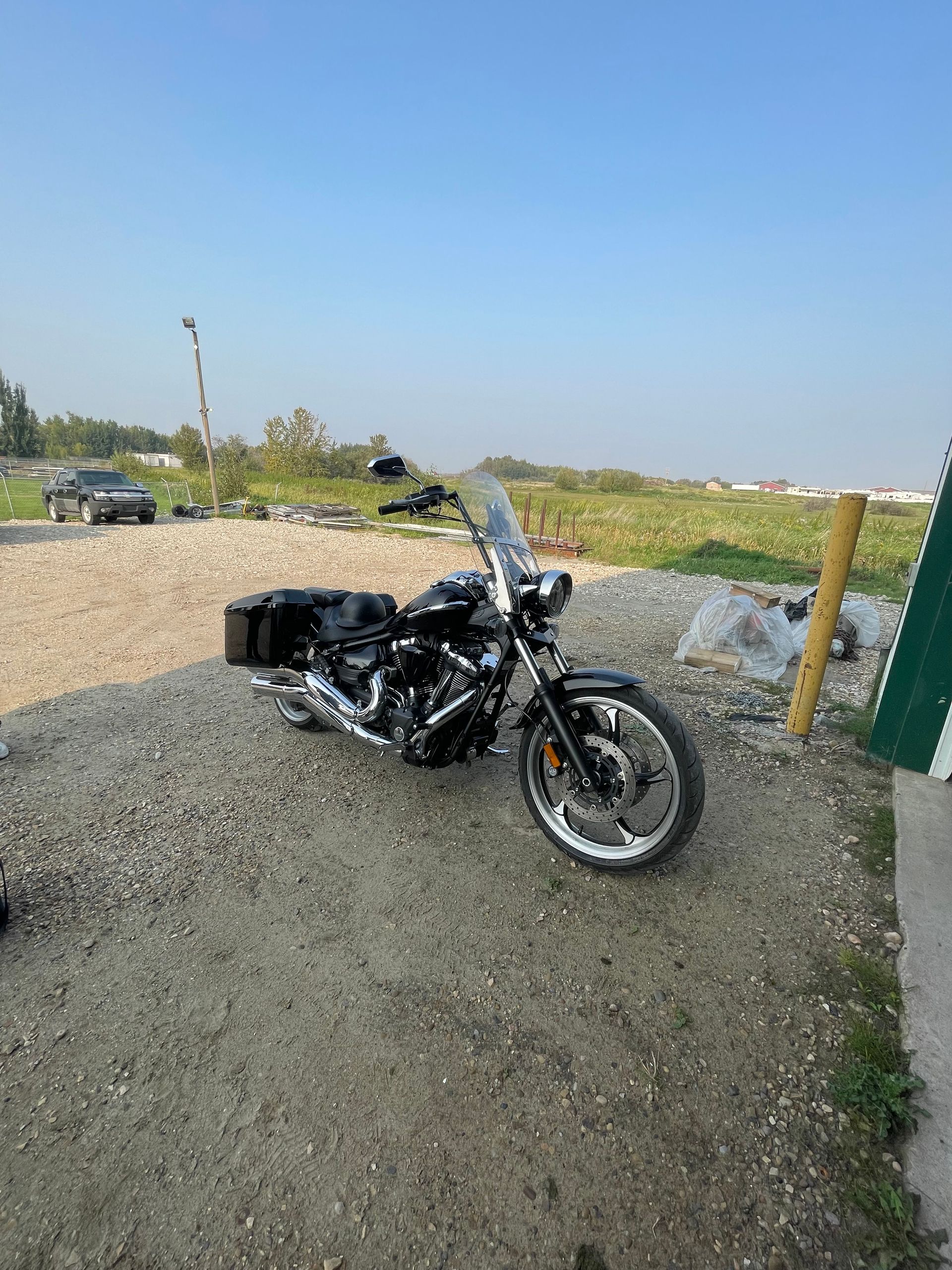A black motorcycle is parked in a gravel lot.