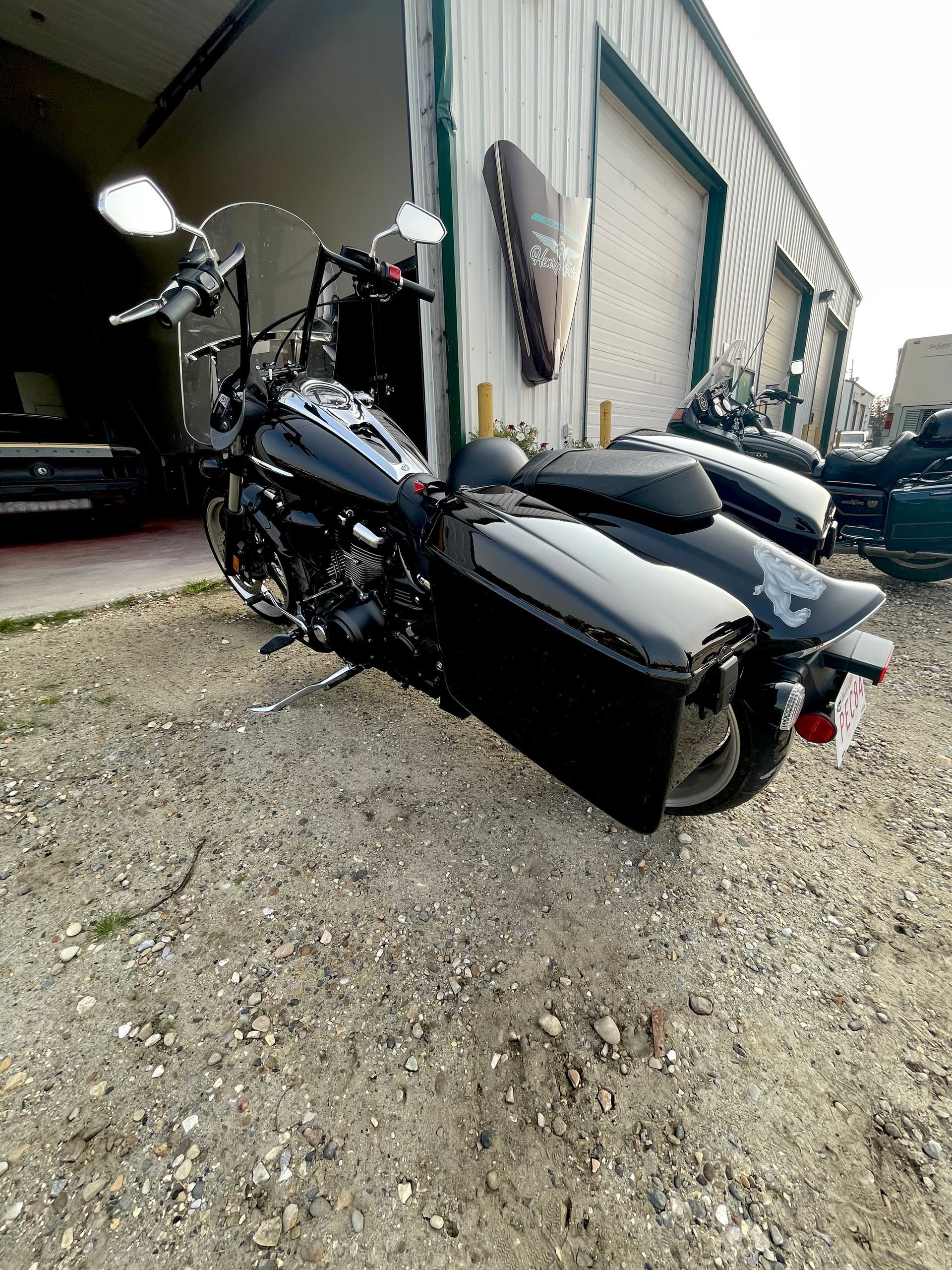 A black motorcycle is parked in front of a garage.