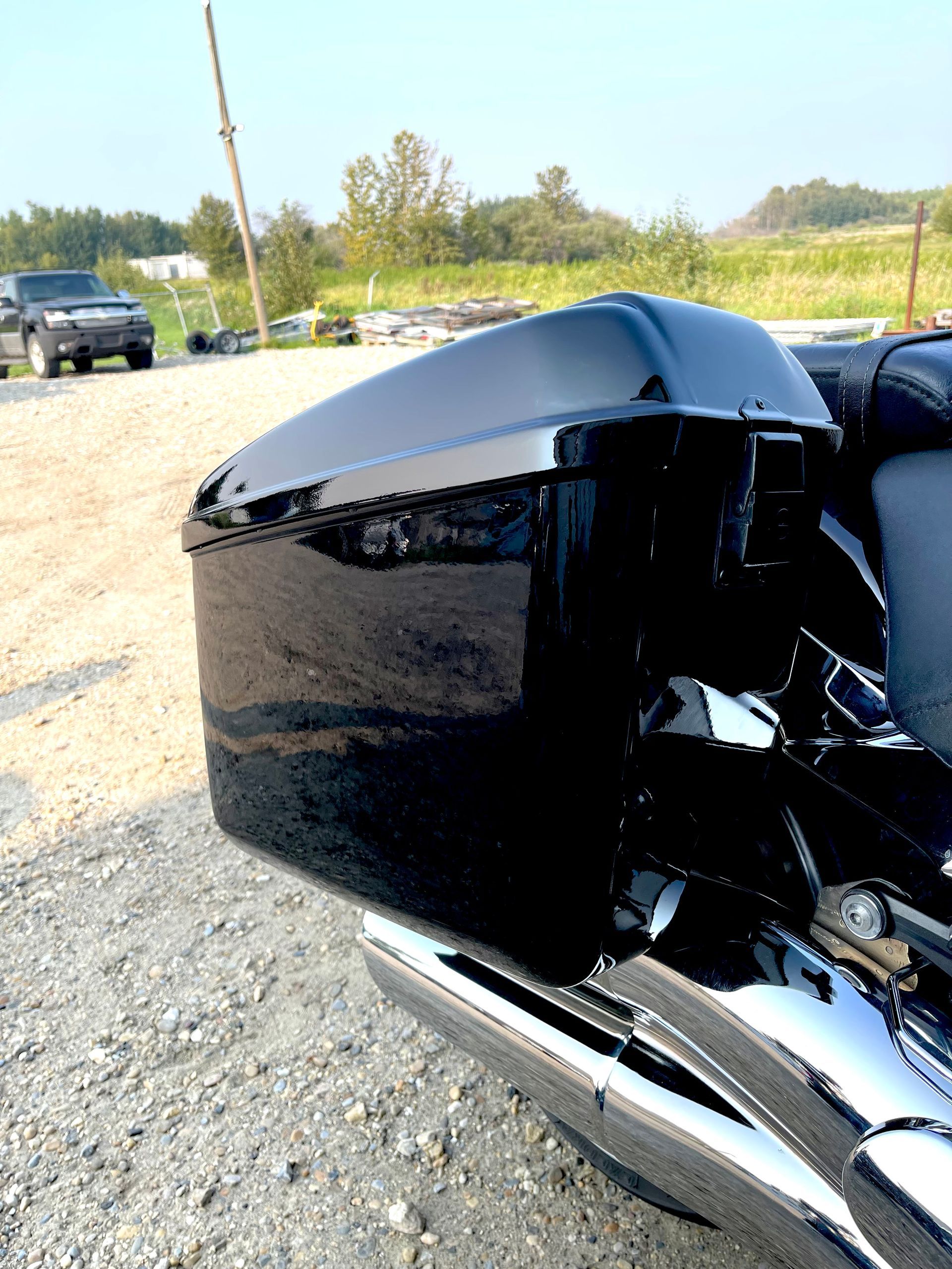 A black motorcycle is parked in a gravel lot.