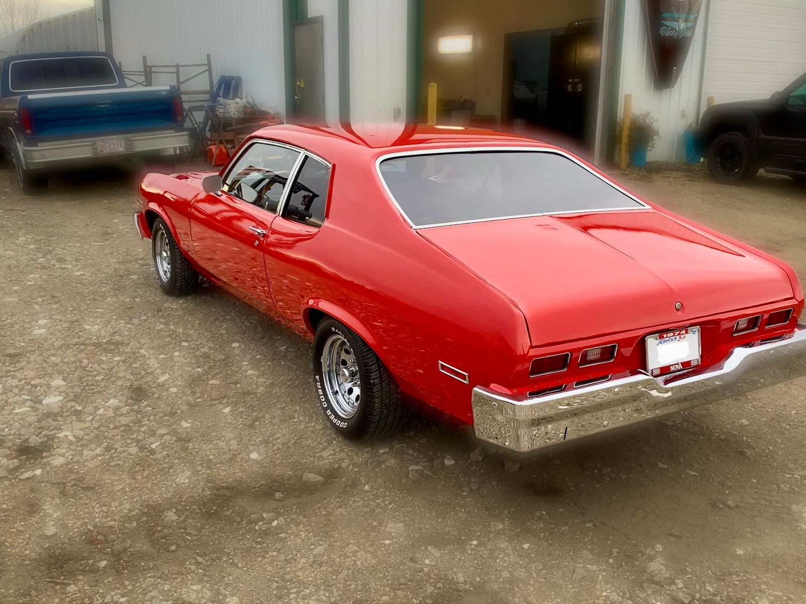 A red car is parked in front of a garage