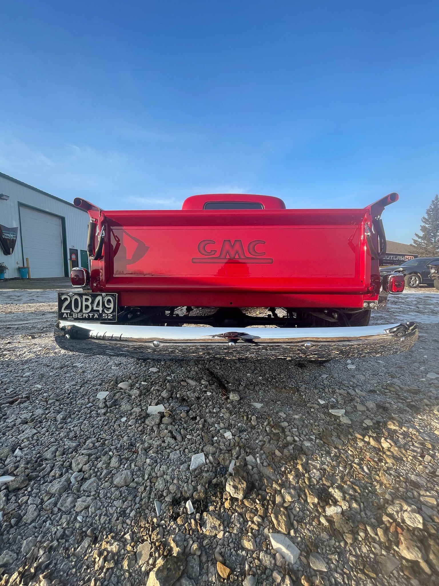 A red truck is parked in a gravel lot.