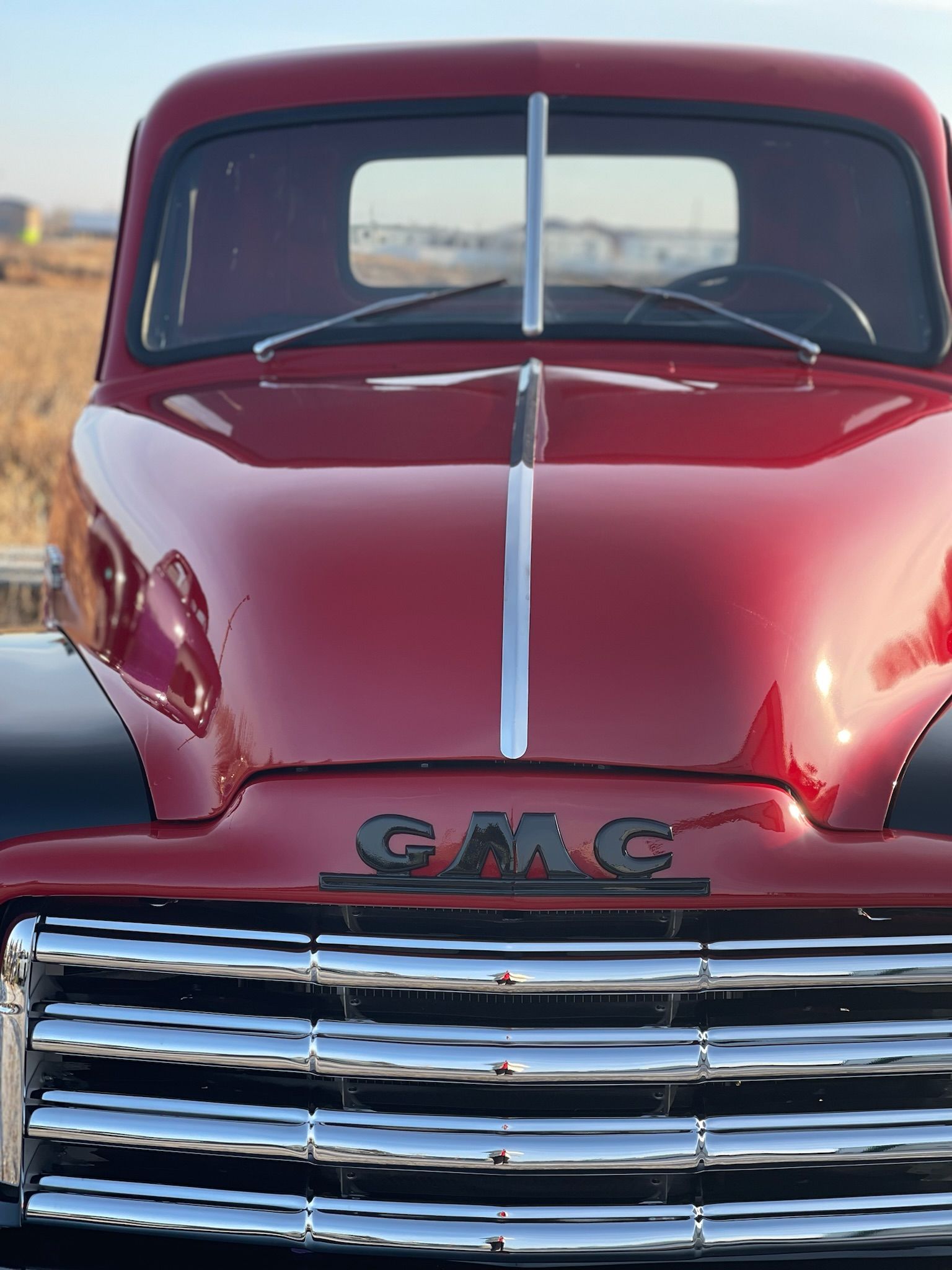 A red gmc truck is parked in a field.