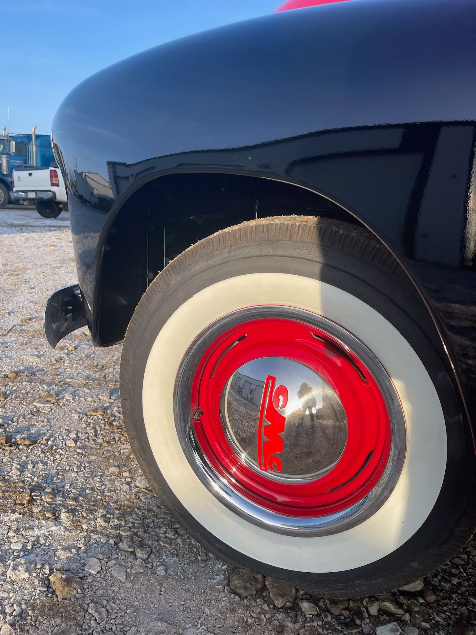 A black car with white tires and a red rim