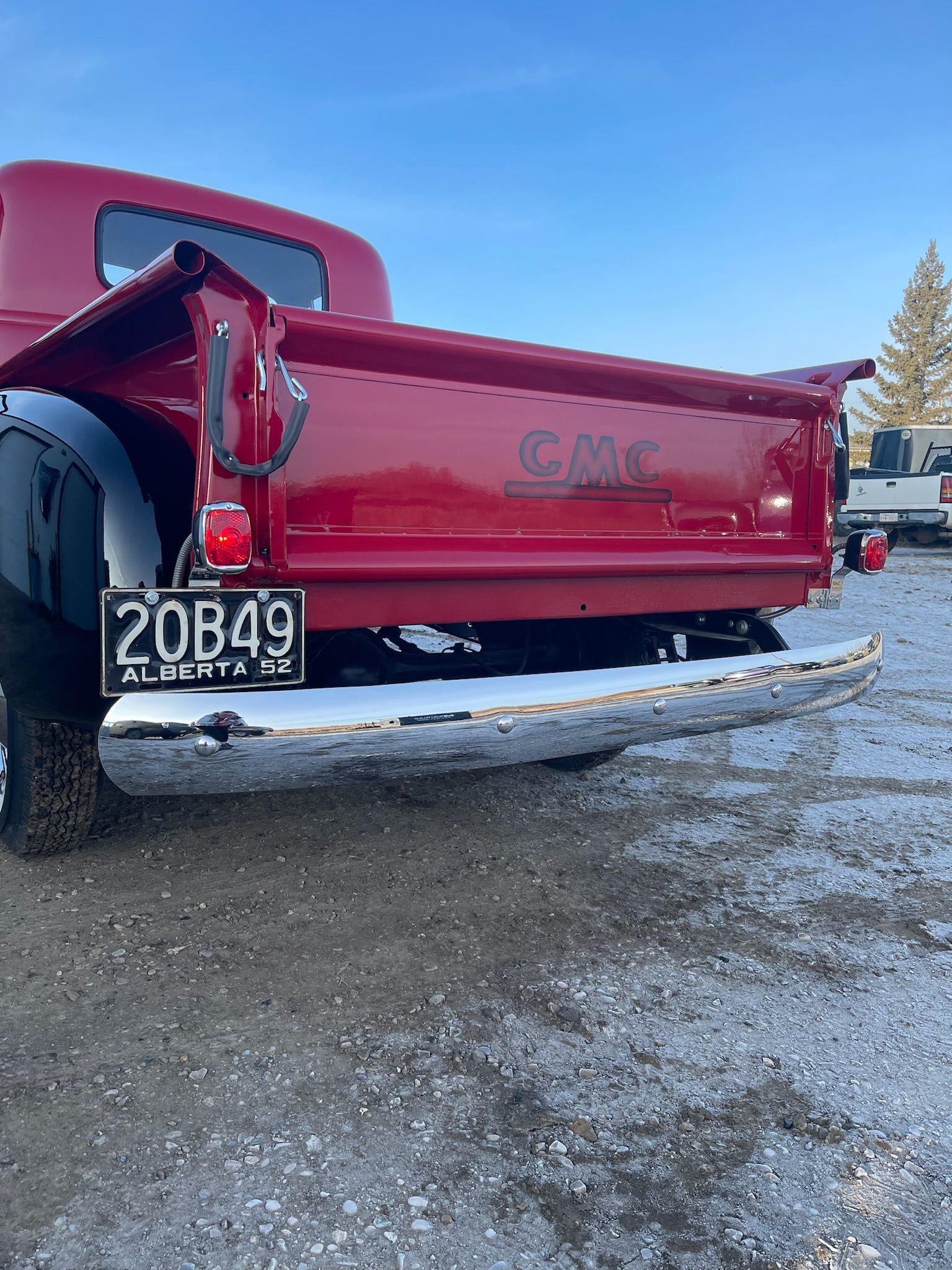 A red truck with a license plate that says 20b49 is parked in the snow.