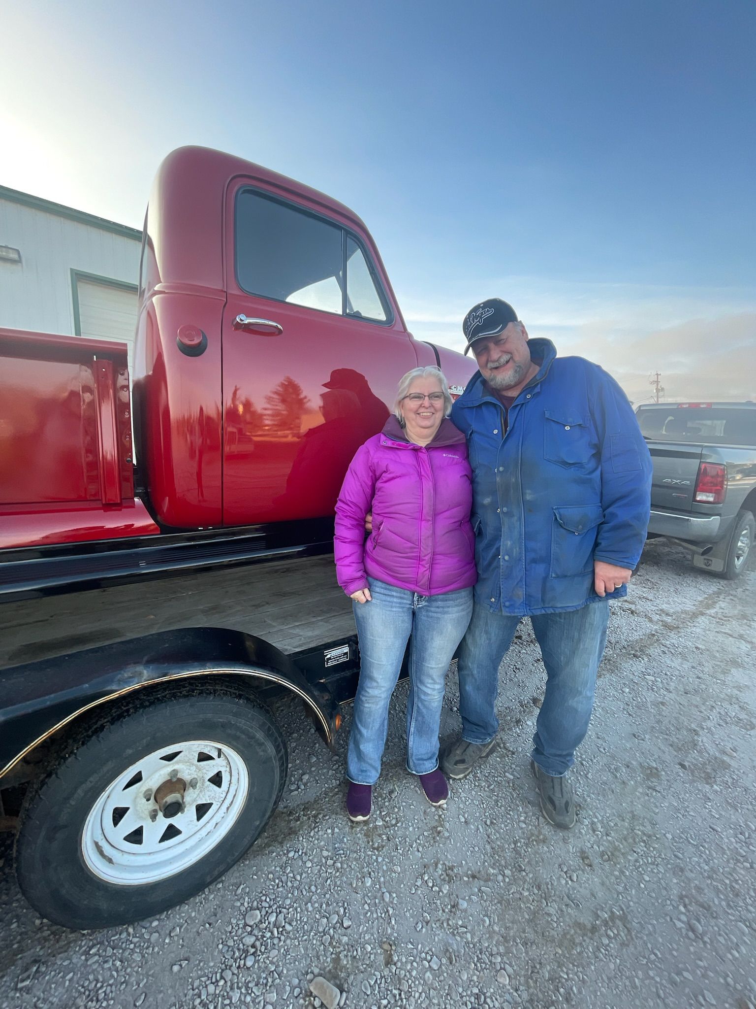 A man and a woman are standing in front of a red truck.