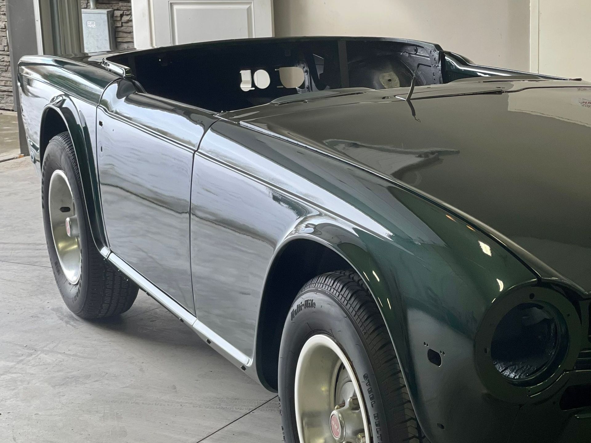 A green sports car is parked in a garage