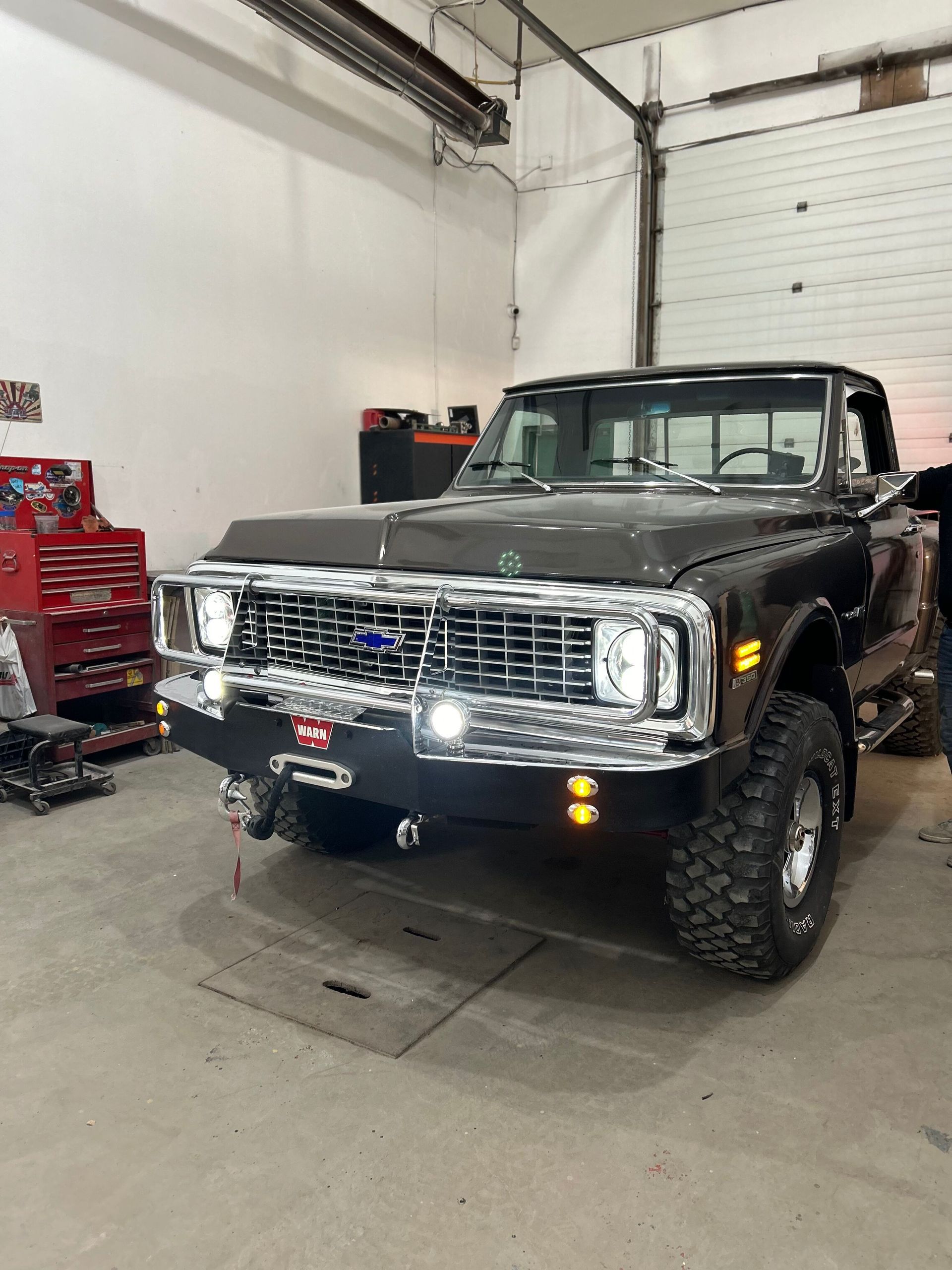 A black truck is parked in a garage next to a red toolbox.