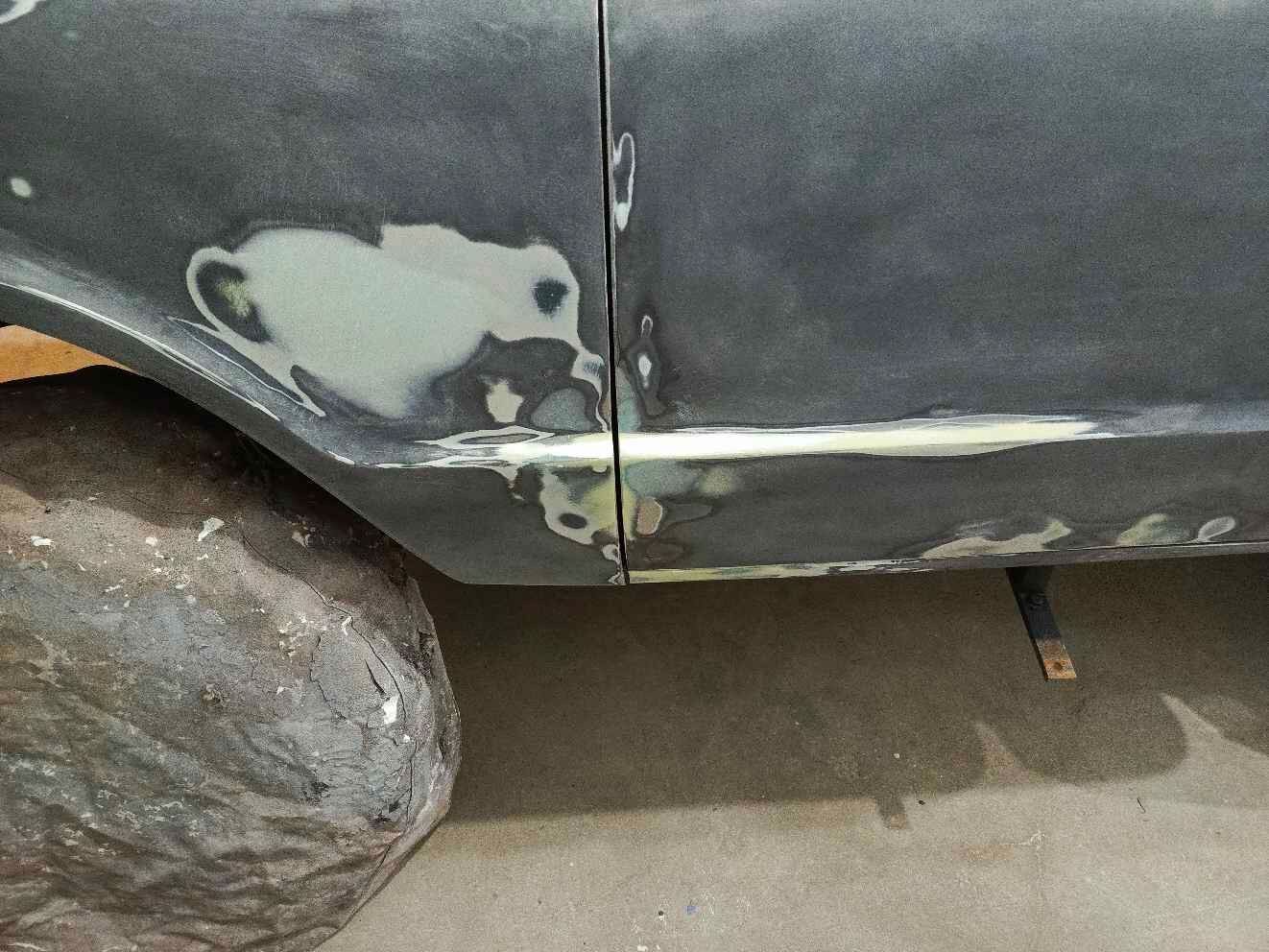 The side of a black car is being painted.