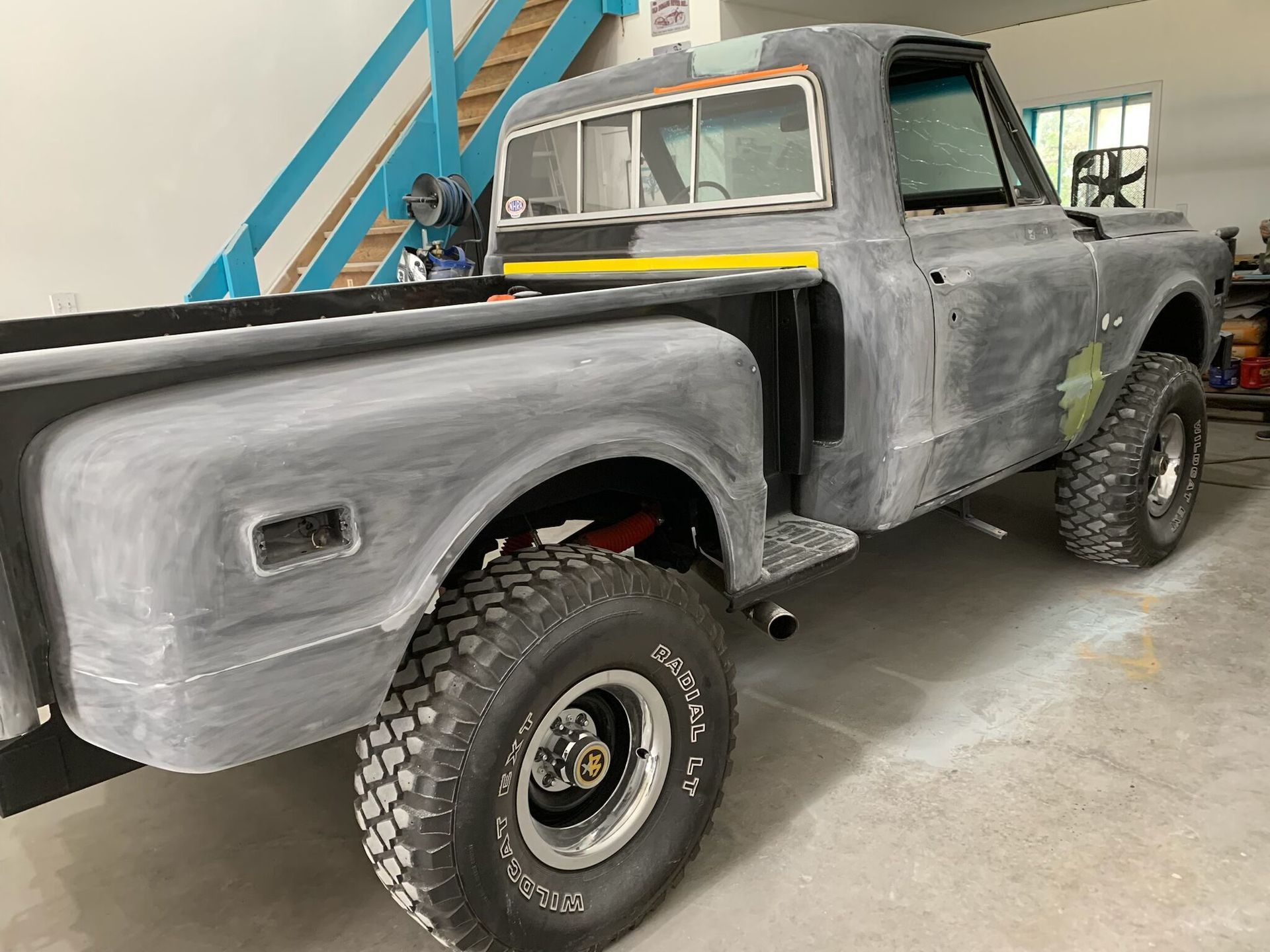 A gray truck is parked in a garage with stairs in the background.