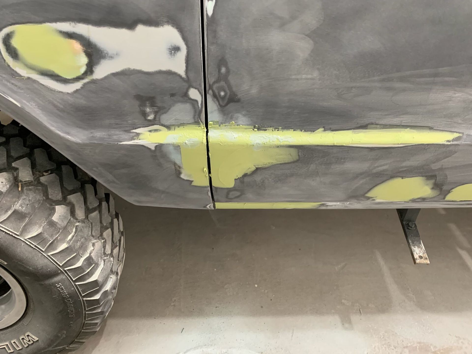 A close up of a car 's side with a tire in the background.