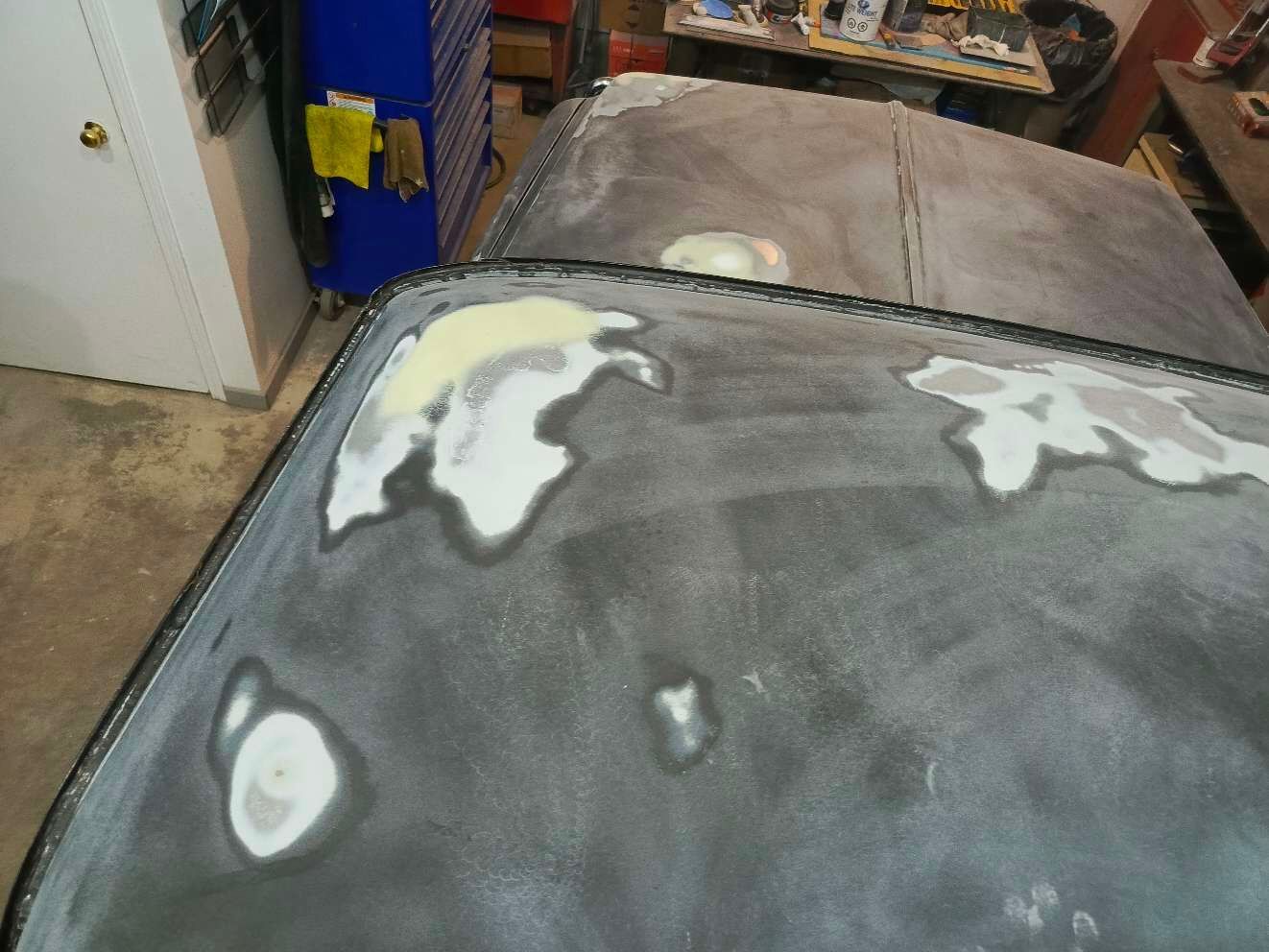The roof of a car is being painted in a garage.