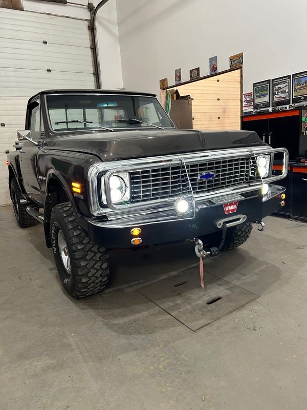 A black truck is parked in a garage next to a garage door.