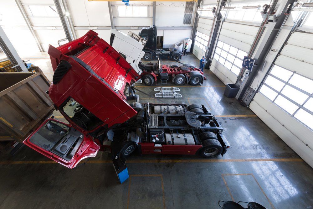 A Red Truck Is Being Repaired in A Garage with Its Hood Up — Fletcher's Truck and 4WD Repair Centre in Hallidays Point, NSW