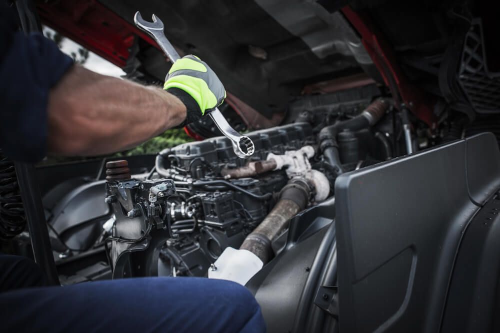A man is working on a truck engine with a wrench — Fletcher's Truck and 4WD Repair Centre in Tuncurry, NSW