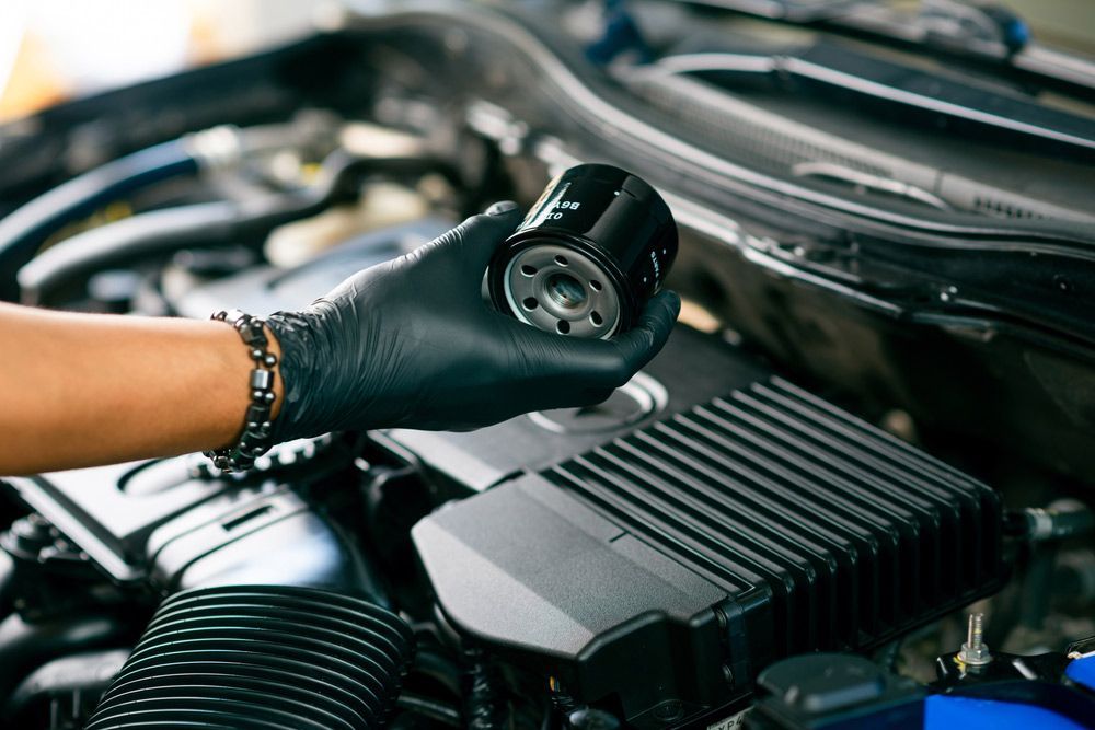 A Person Holding a Oil Filter Over a Car Engine — Fletcher's Truck and 4WD Repair Centre in Forster, NSW