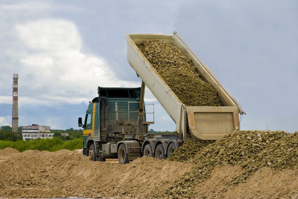 A Dump Truck Is Dumping Dirt Into a Pile of Dirt — Fletcher's Truck and 4WD Repair Centre in Hallidays Point, NSW
