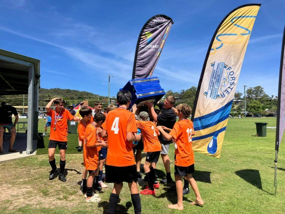 A Group of Young Boys Are Holding a Trophy in A Field — Fletcher's Truck and 4WD Repair Centre in Forster, NSW
