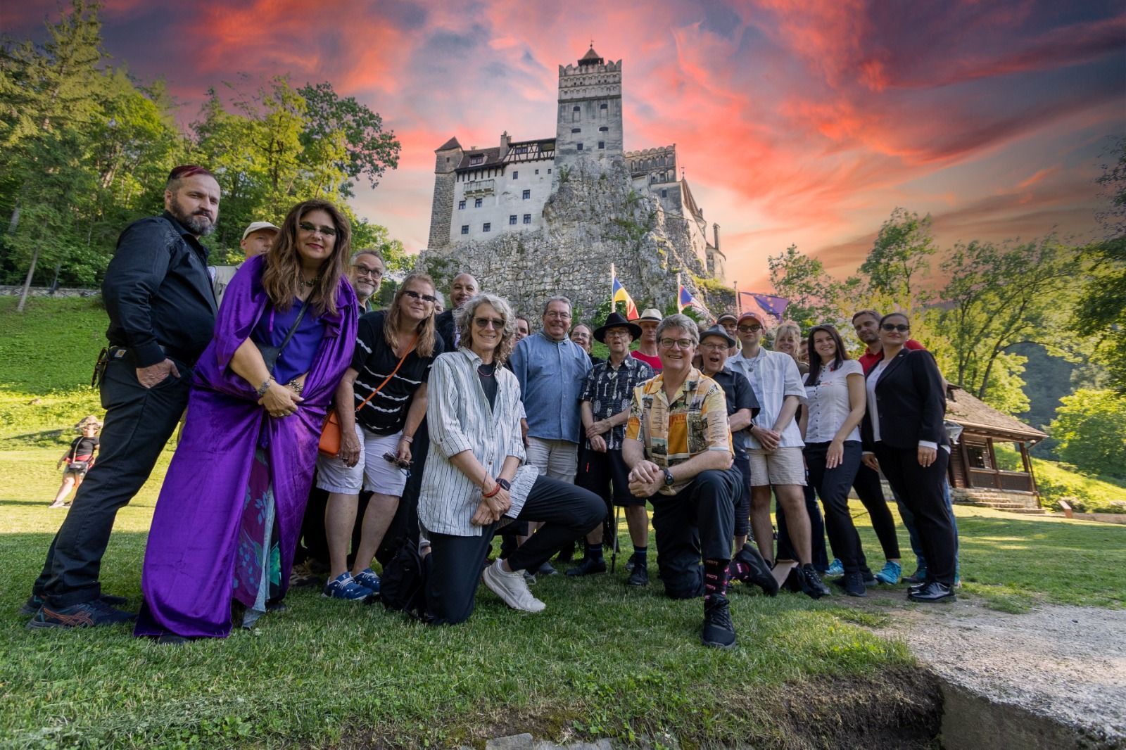 Gruppposer framför Bran slott, Rumänien, under en dramatisk solnedgång.
