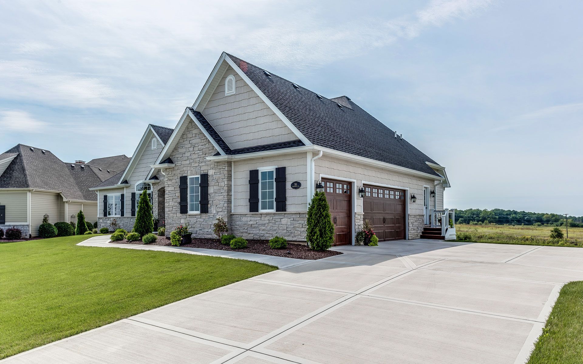 A large white house with a black roof is sitting on top of a lush green field.