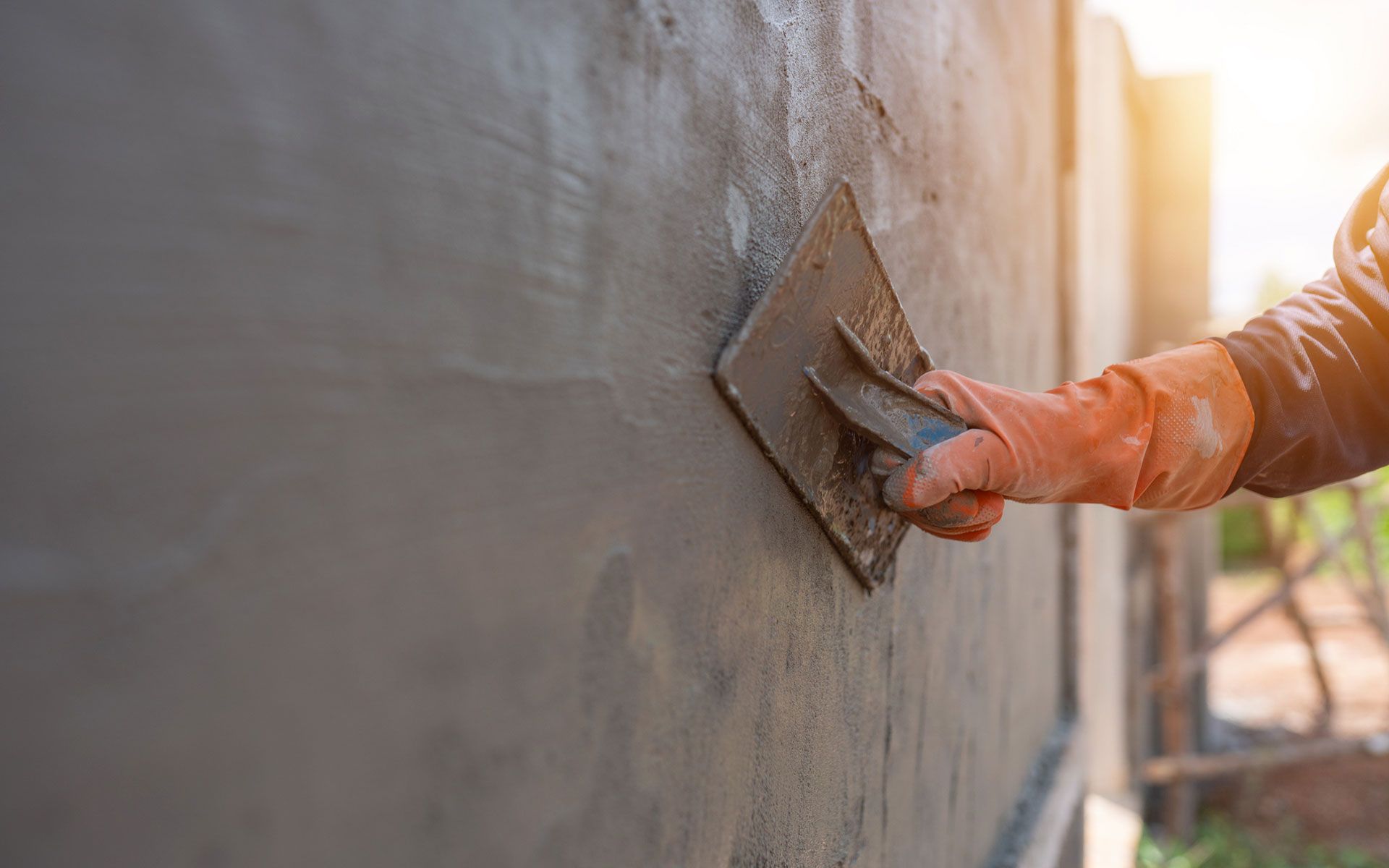 A person is plastering a wall with a trowel.