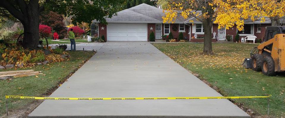 A concrete driveway is being built in front of a house.