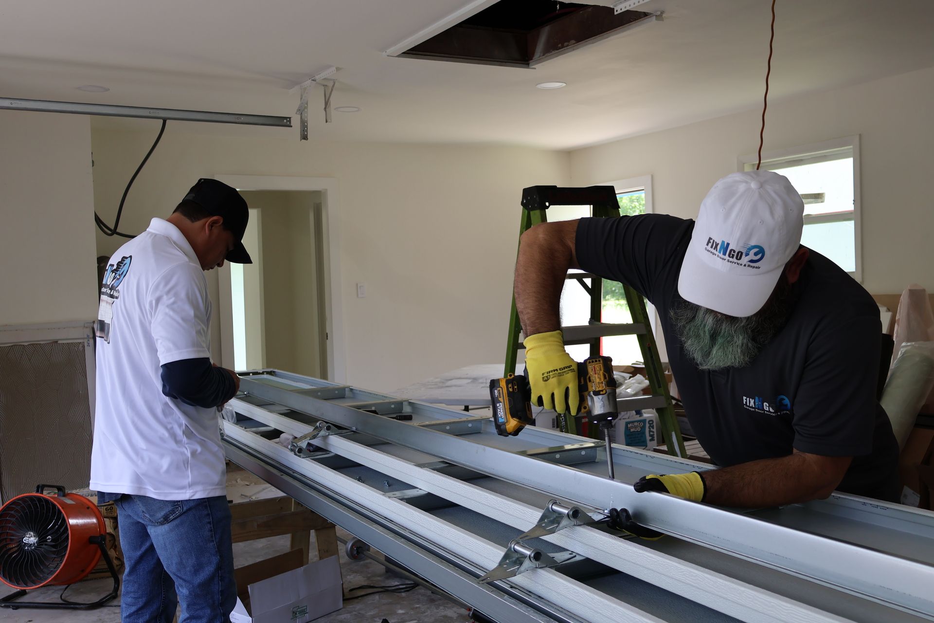 Two workers installing a metal ceiling frame in a room under renovation
